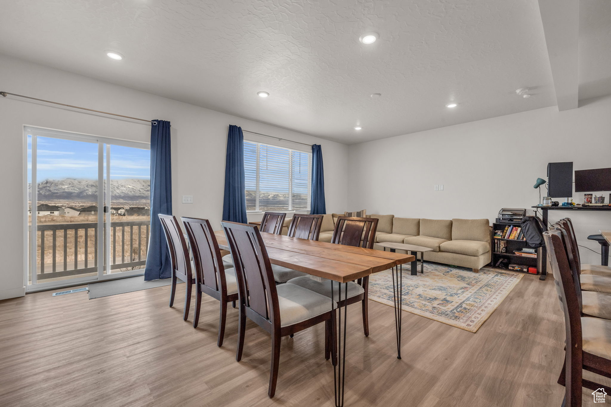 Dining area with light hardwood / wood-style flooring, a textured ceiling, and a healthy amount of sunlight