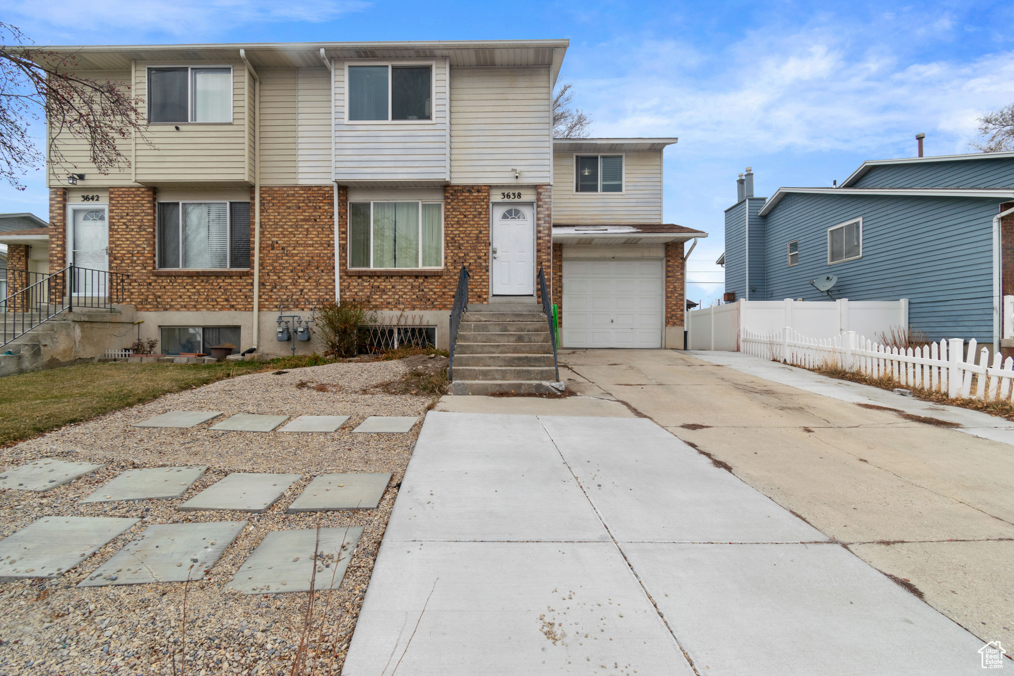 View of front of house featuring fence, brick siding, an attached garage, and concrete driveway