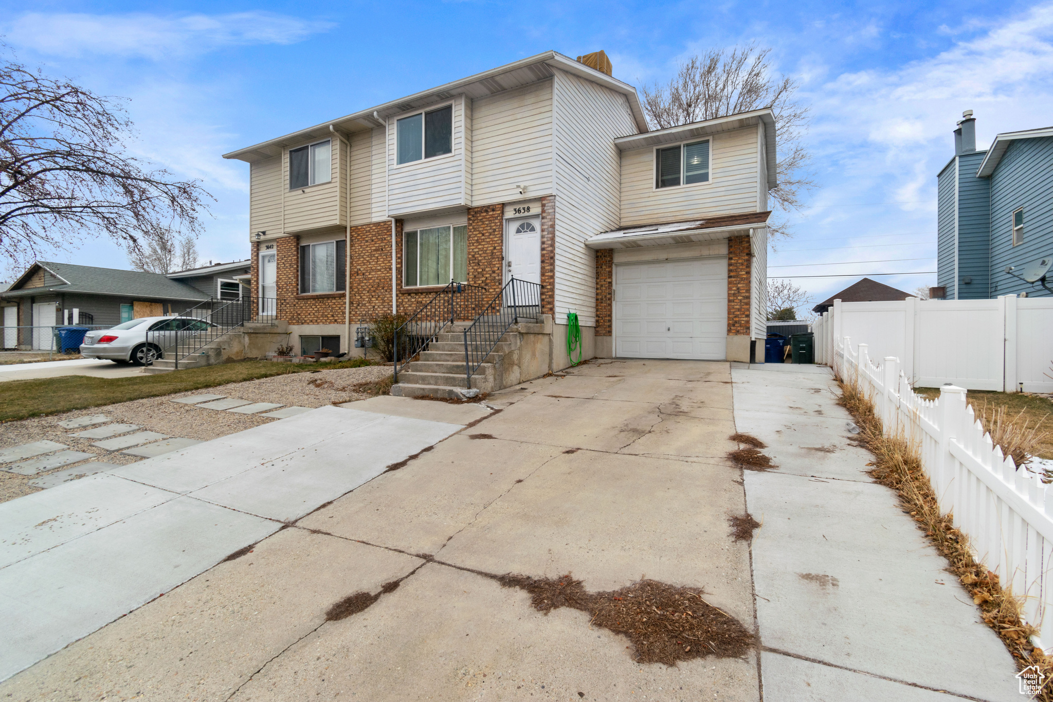 View of front of home featuring fence, driveway, an attached garage, and brick siding