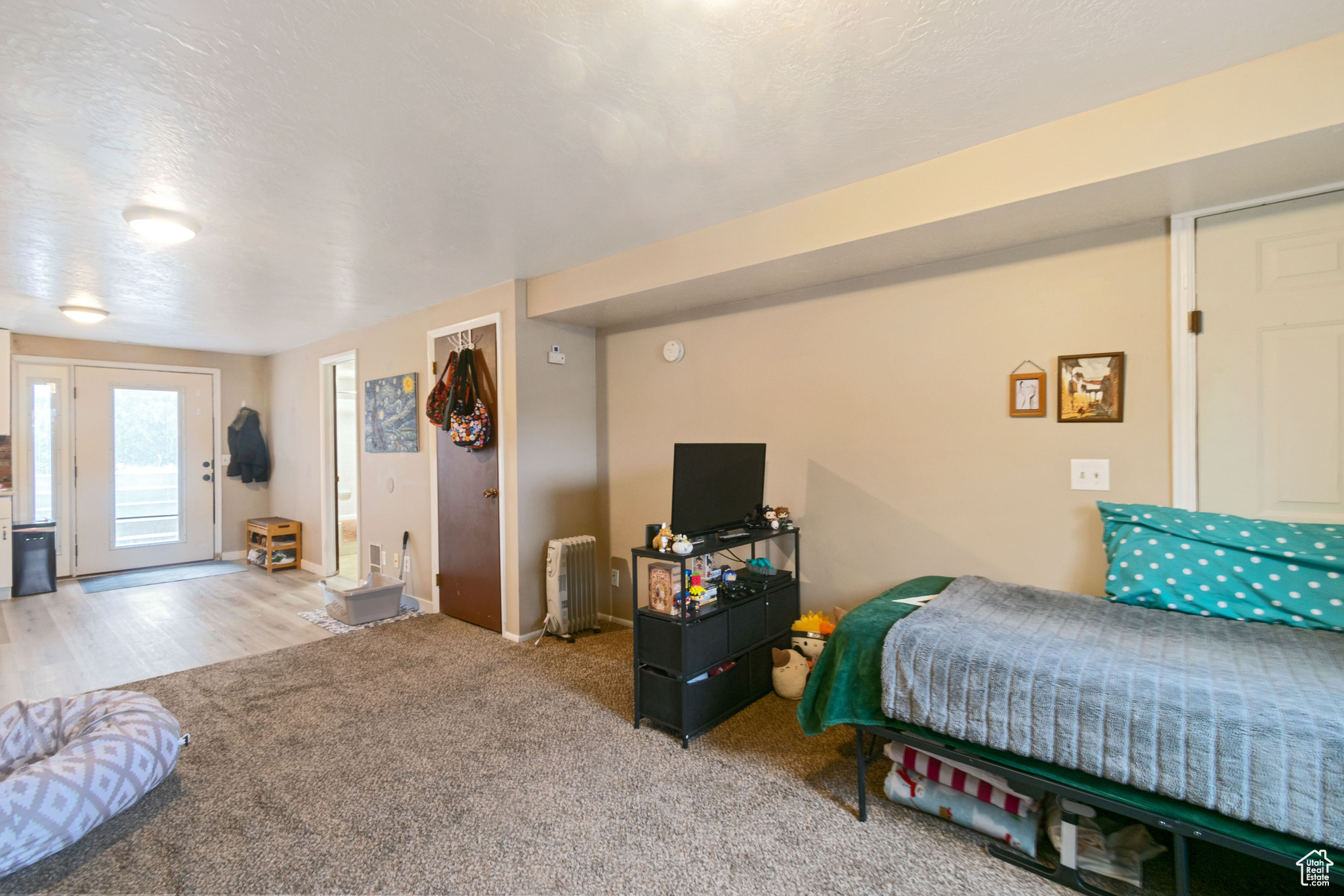 Bedroom with a textured ceiling, light carpet, and radiator heating unit