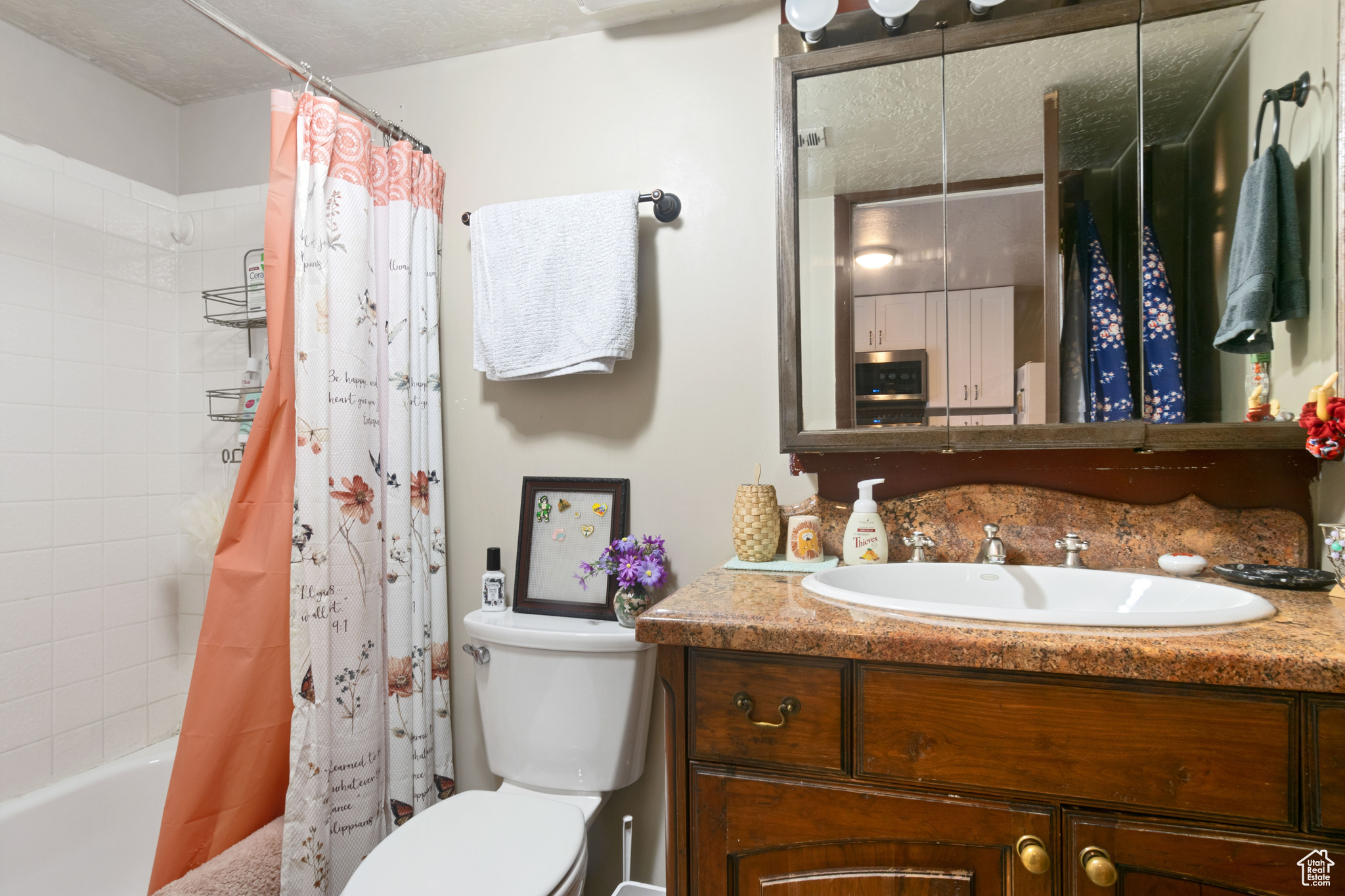 Bathroom featuring vanity, toilet, and shower / bathtub combination with curtain