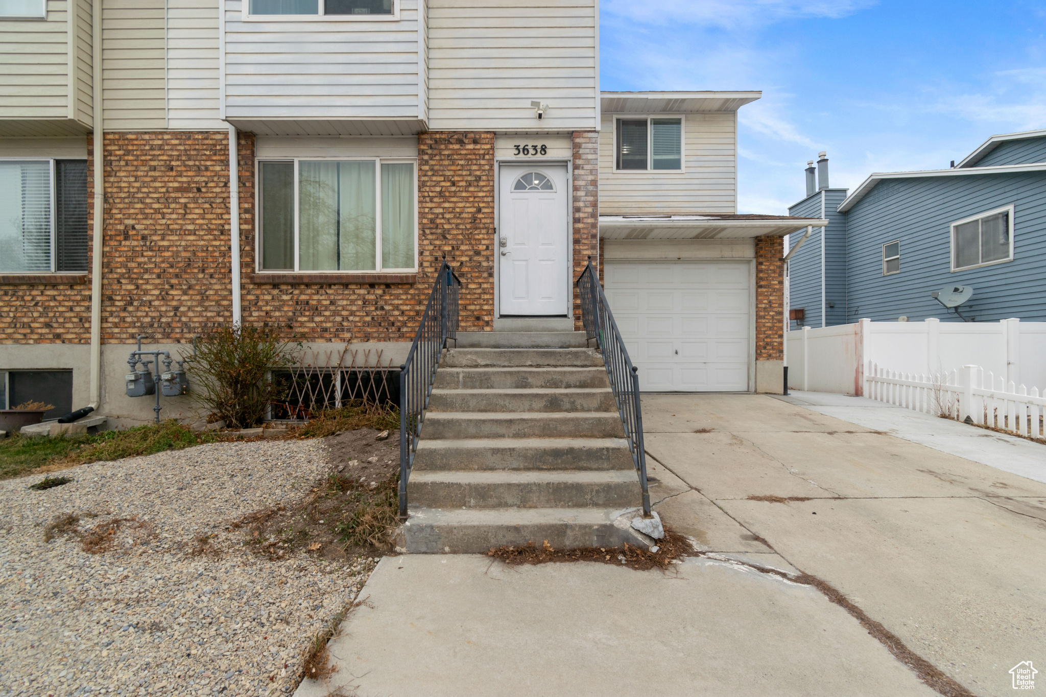 Multi unit property with fence, driveway, an attached garage, and brick siding