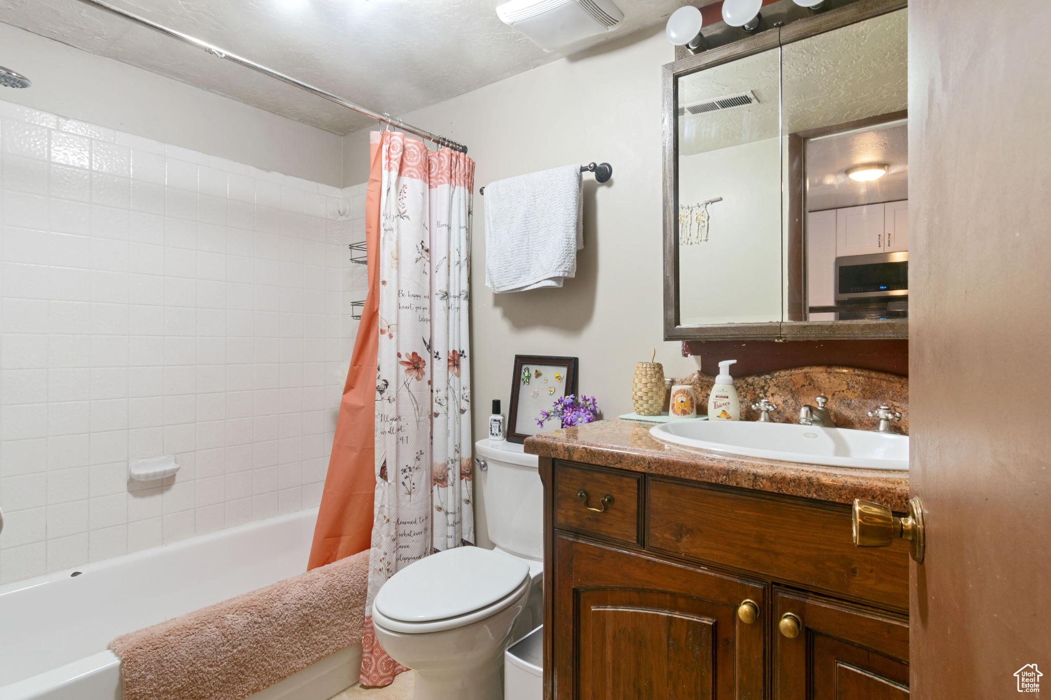 Full bathroom with vanity, toilet, shower / bath combination with curtain, and visible vents