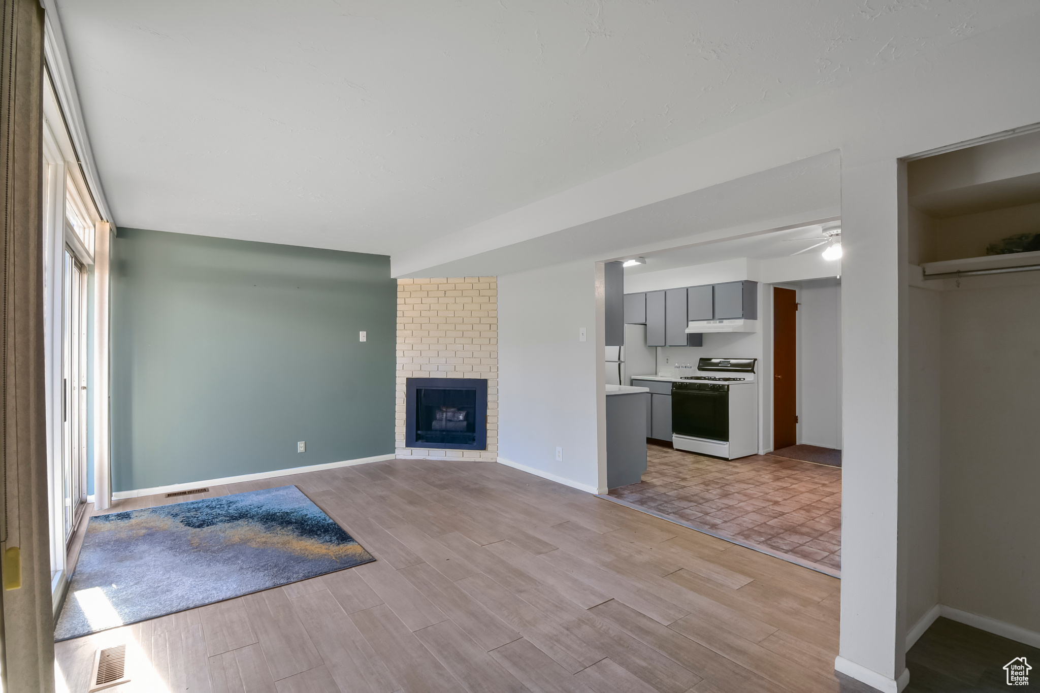 Unfurnished living room featuring light wood-type flooring, ceiling fan, a fireplace, and baseboards
