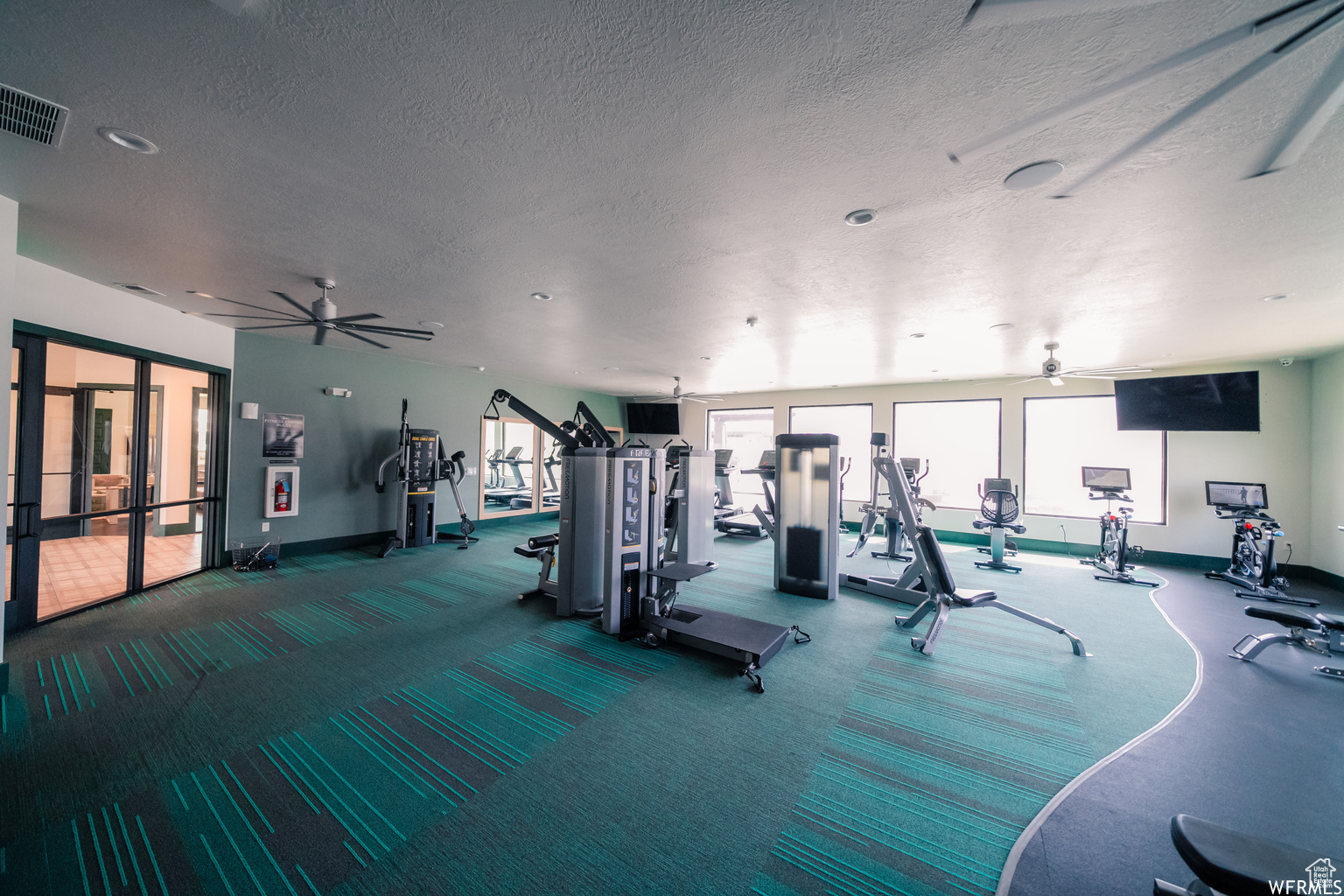 Workout area with baseboards, ceiling fan, visible vents, and a textured ceiling