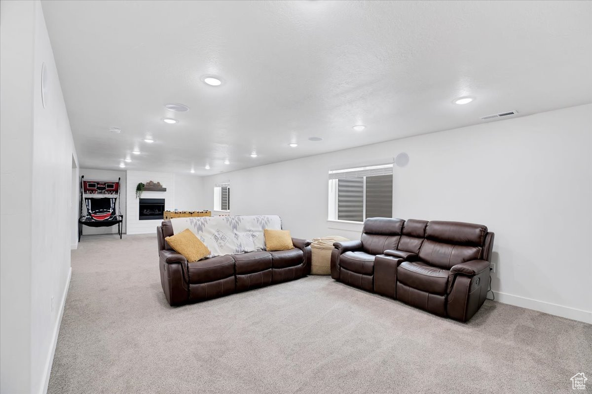 Living room featuring light carpet, visible vents, baseboards, a fireplace, and recessed lighting