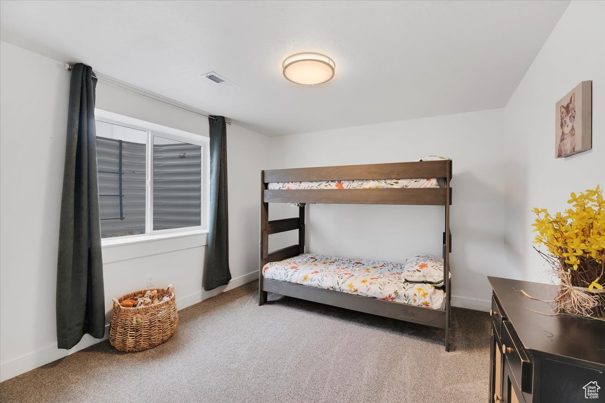 Carpeted bedroom with baseboards and visible vents