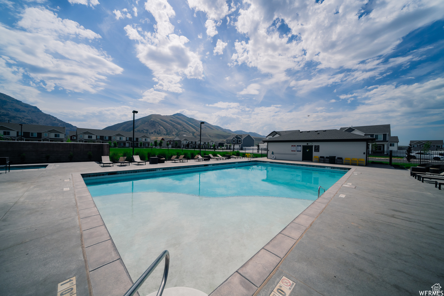 Community pool featuring a patio area, a residential view, fence, and a mountain view