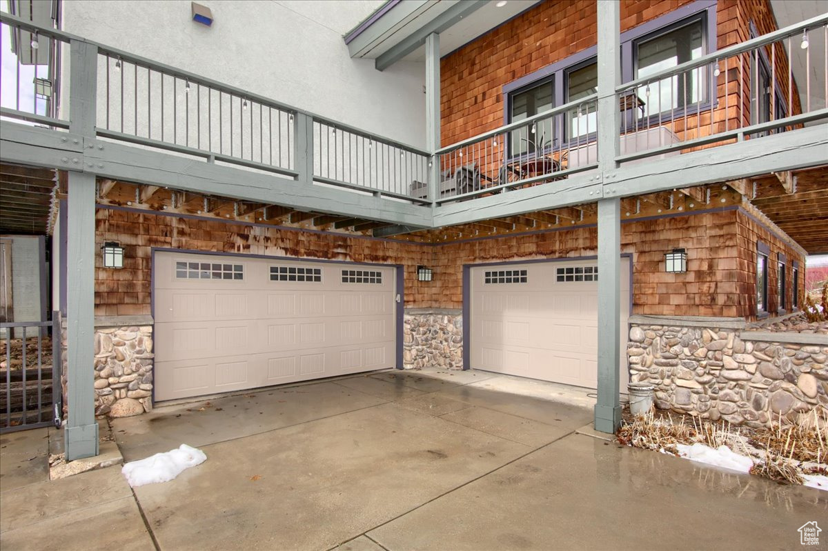 View of side of property with a garage, stone siding, and driveway