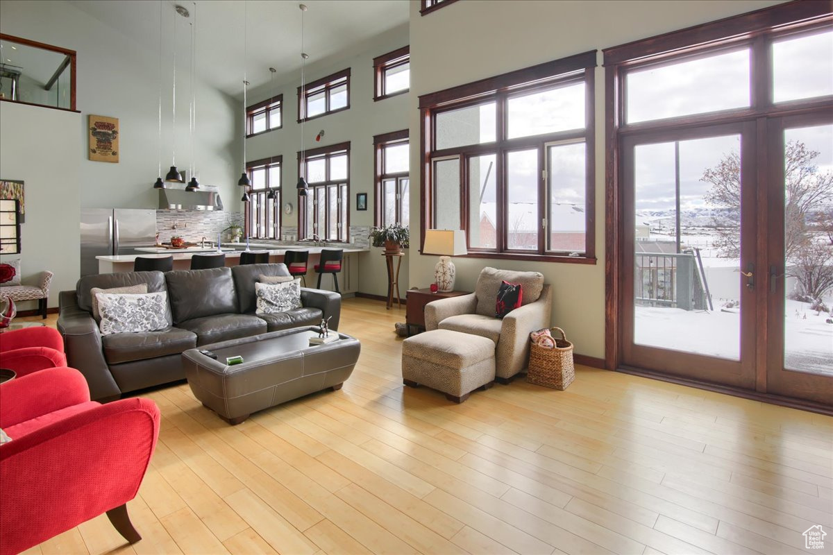 Living room featuring a high ceiling, light wood-style flooring, and baseboards