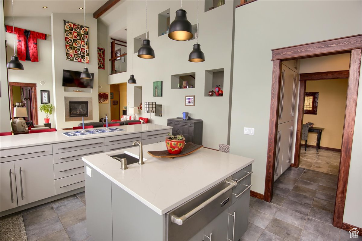 Kitchen featuring a center island with sink, open floor plan, decorative light fixtures, light countertops, and a sink