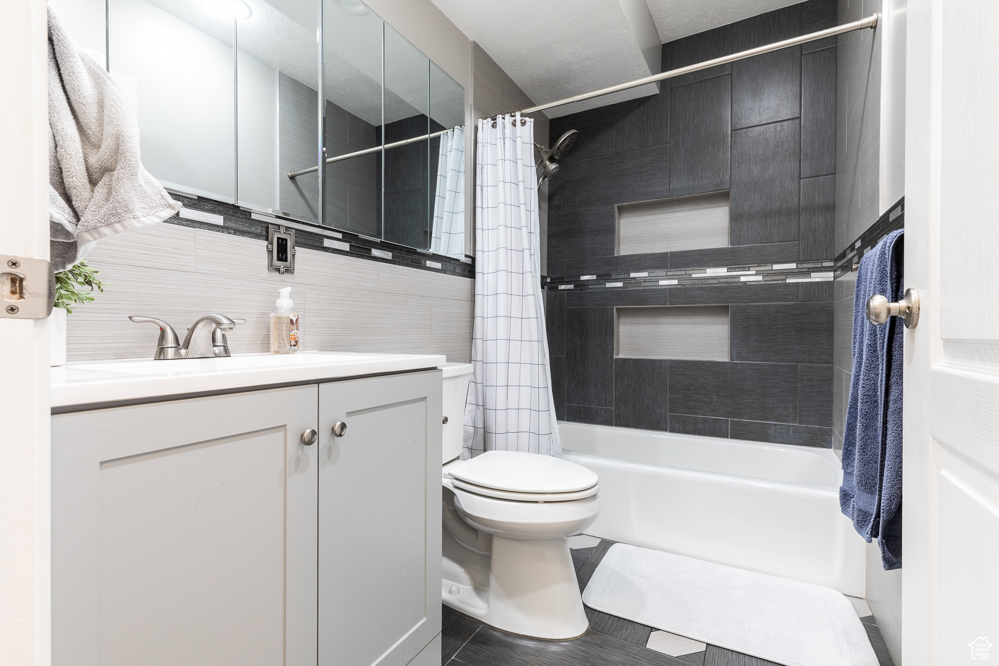 Full bath featuring shower / bathtub combination with curtain, tile walls, vanity, and toilet
