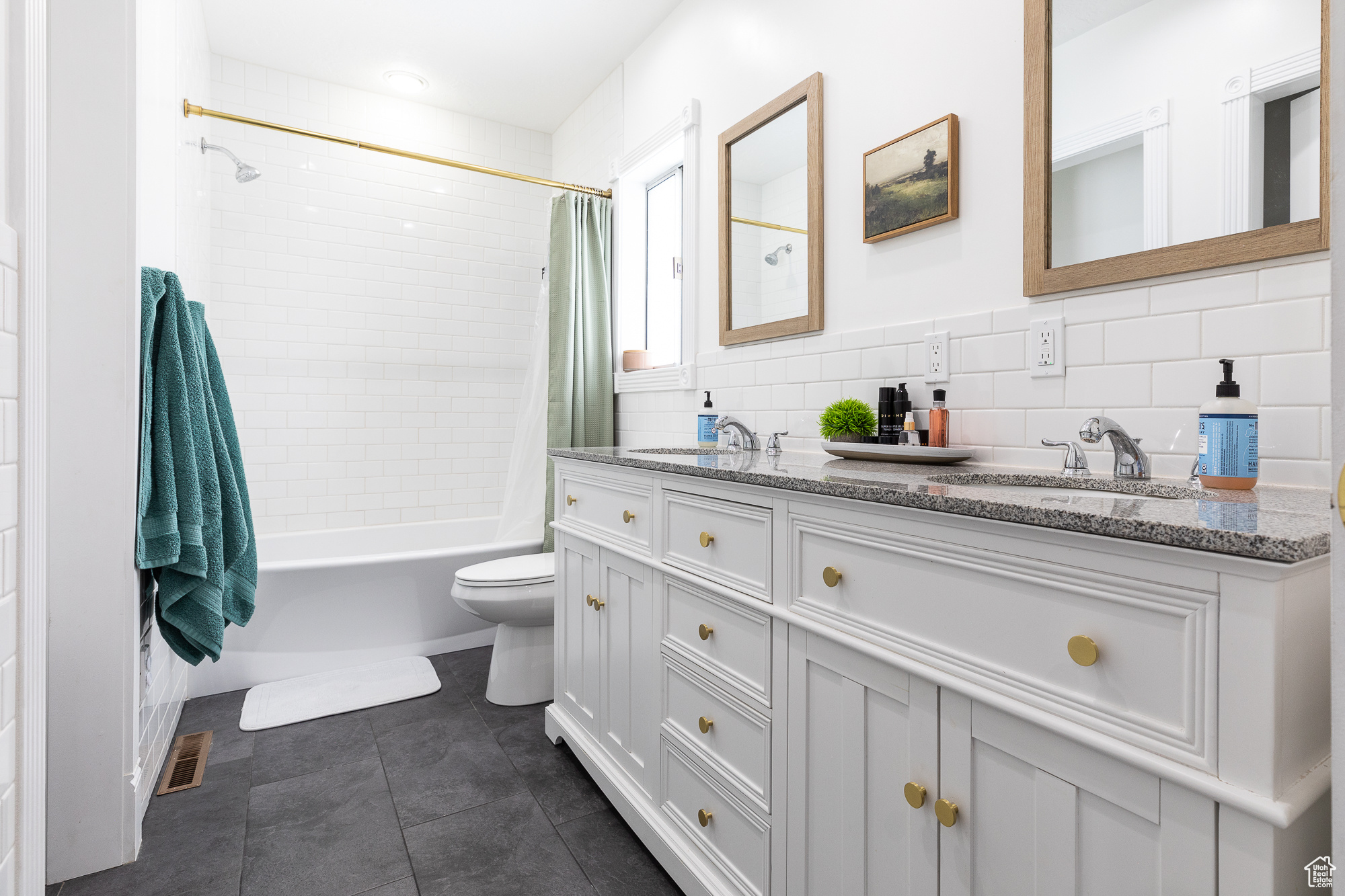 Bathroom with double vanity, visible vents, a sink, shower / bathtub combination with curtain, and tile walls