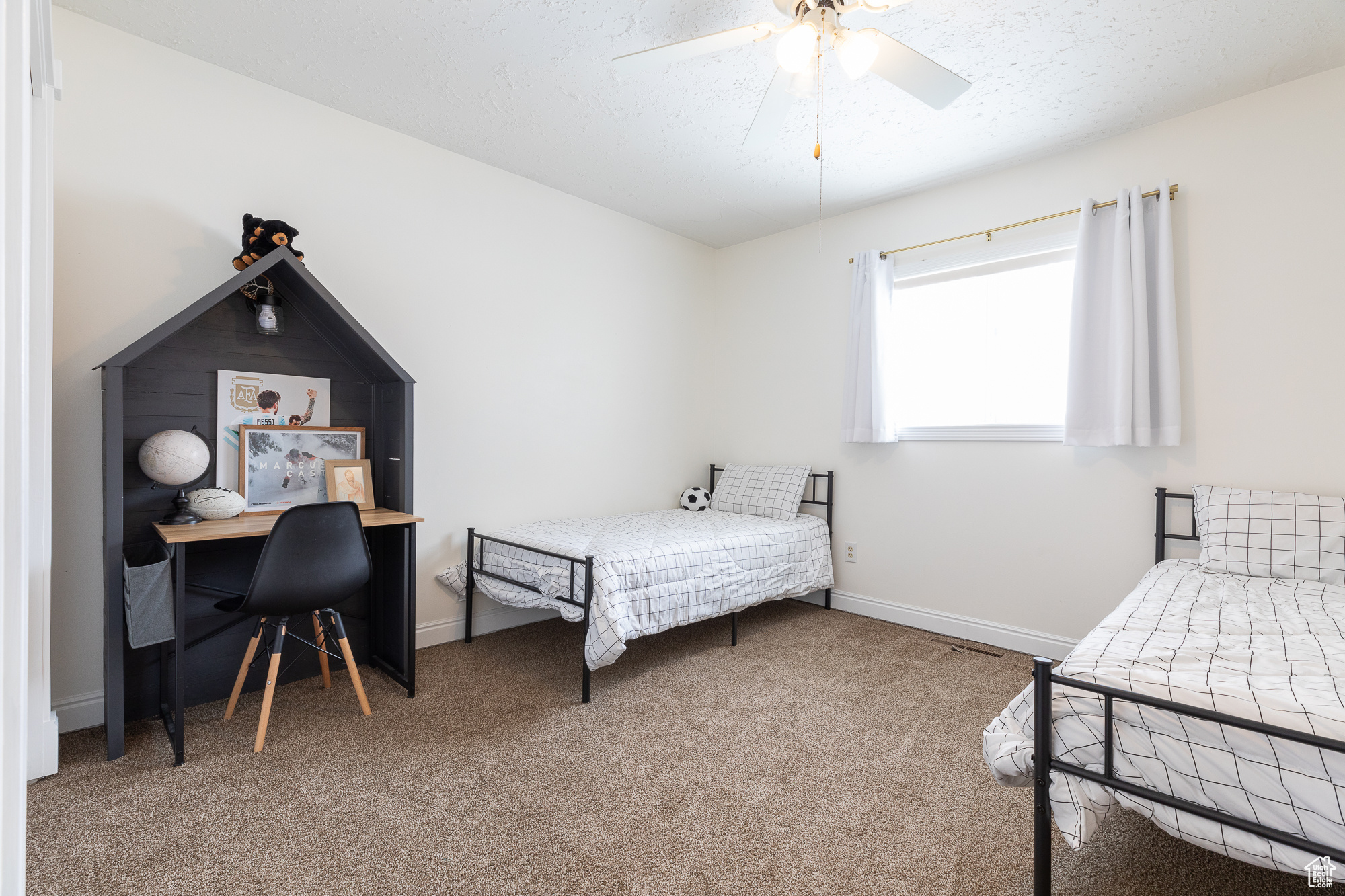 Carpeted bedroom with ceiling fan, baseboards, and a textured ceiling