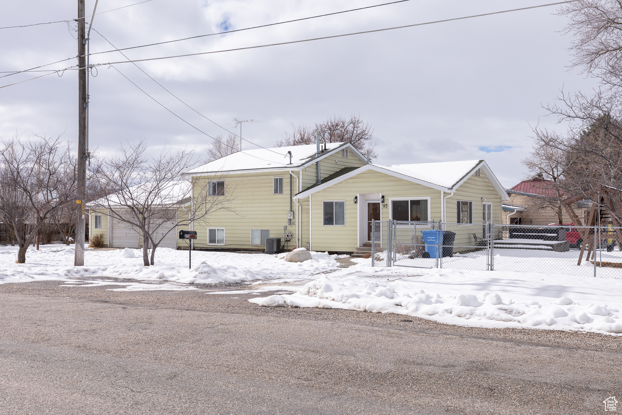 View of front facade with a garage, fence, and cooling unit