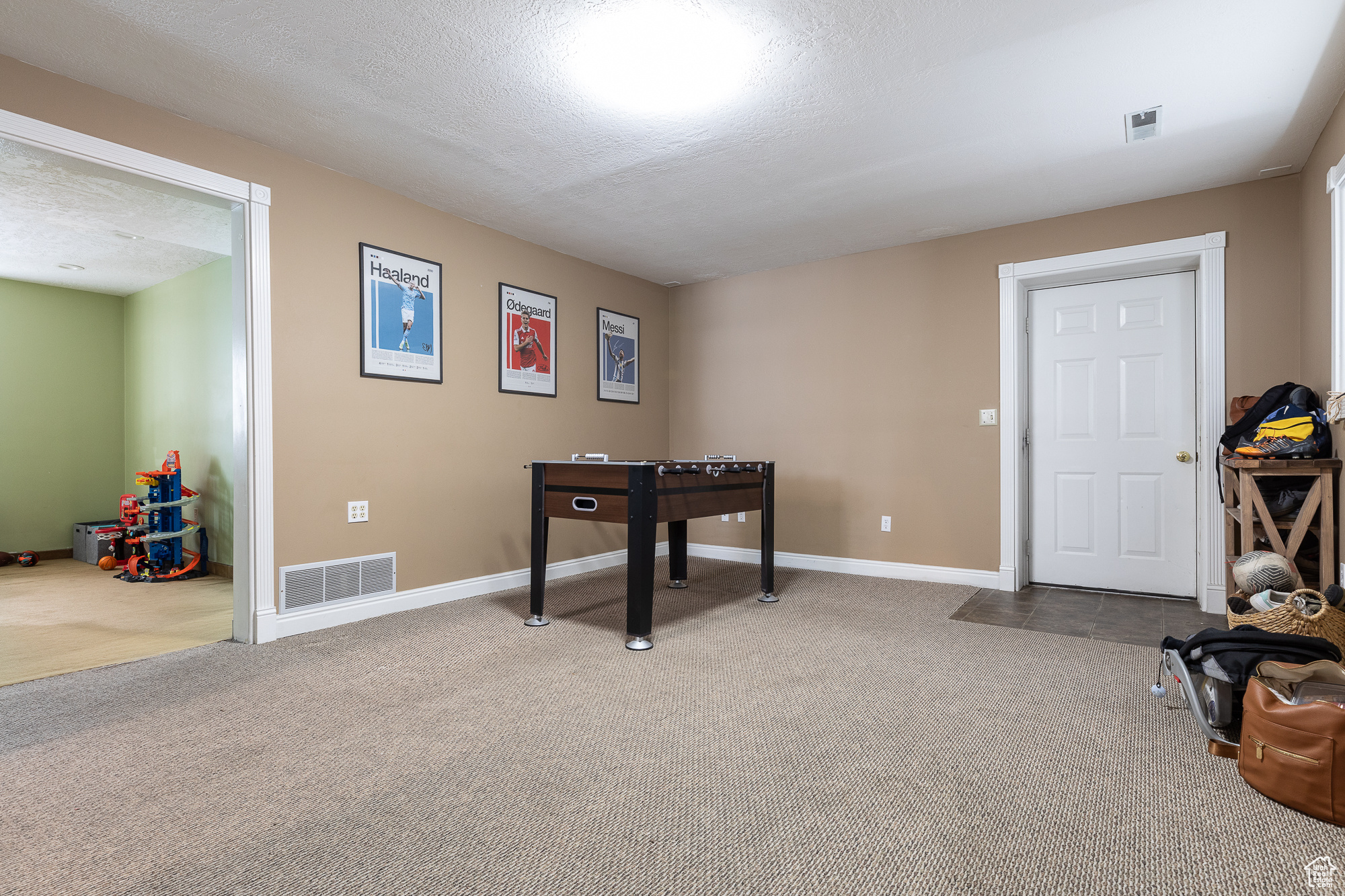 Playroom featuring a textured ceiling, visible vents, and carpet flooring