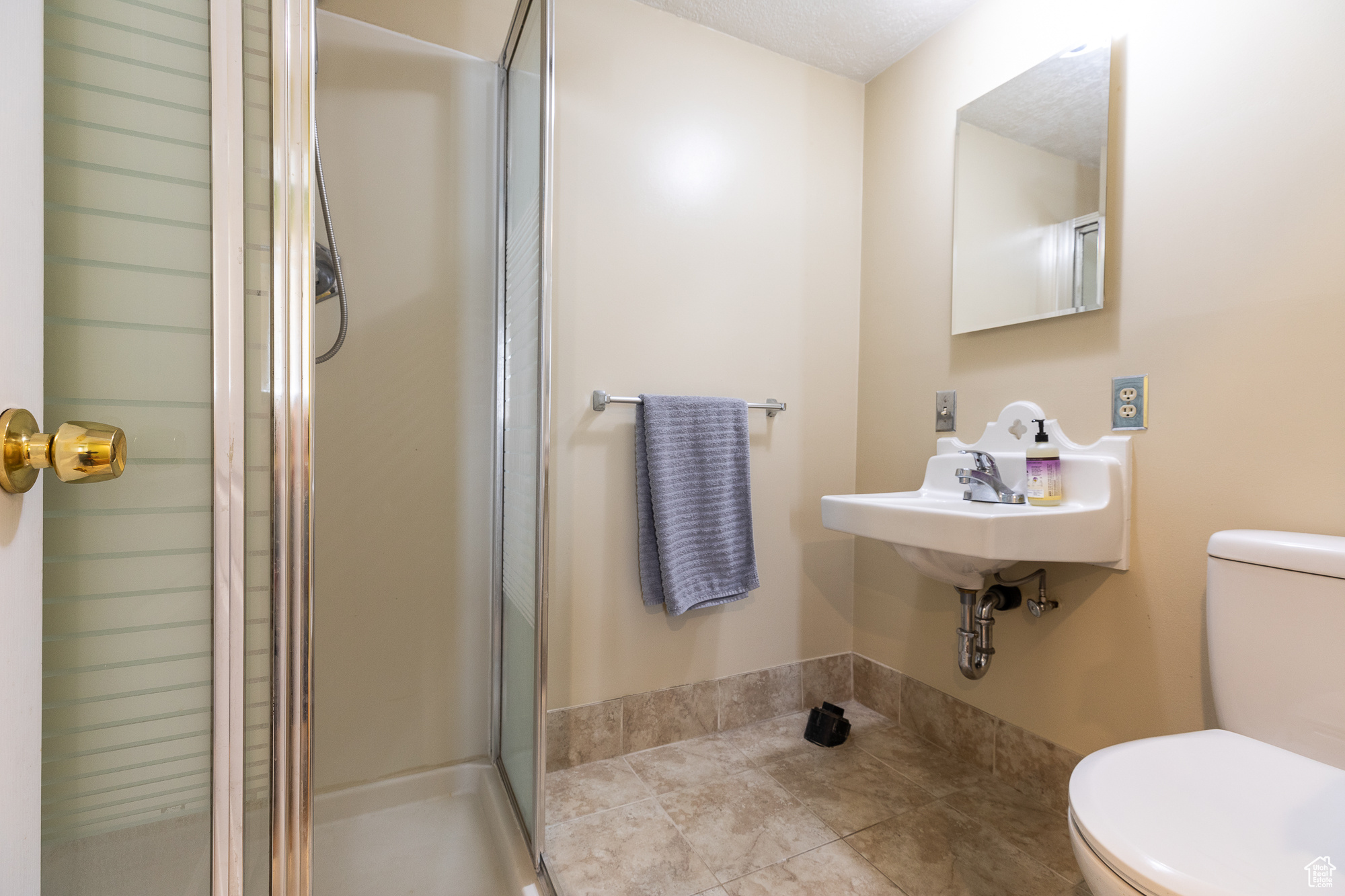 Bathroom featuring a stall shower, a sink, and toilet
