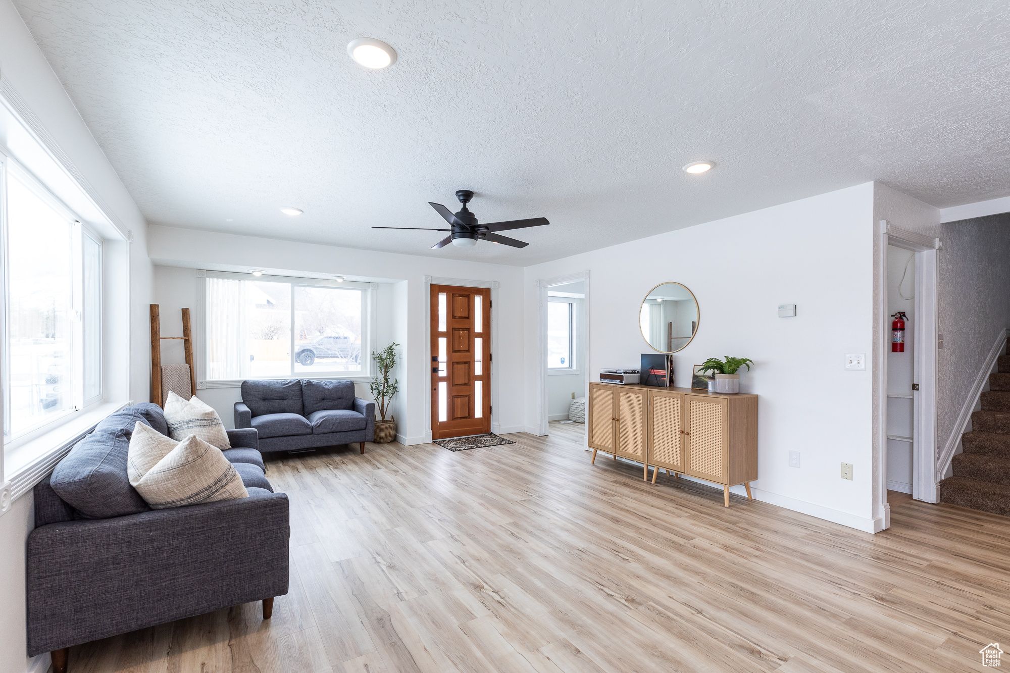 Living room featuring light wood-style floors, a textured ceiling, and stairs