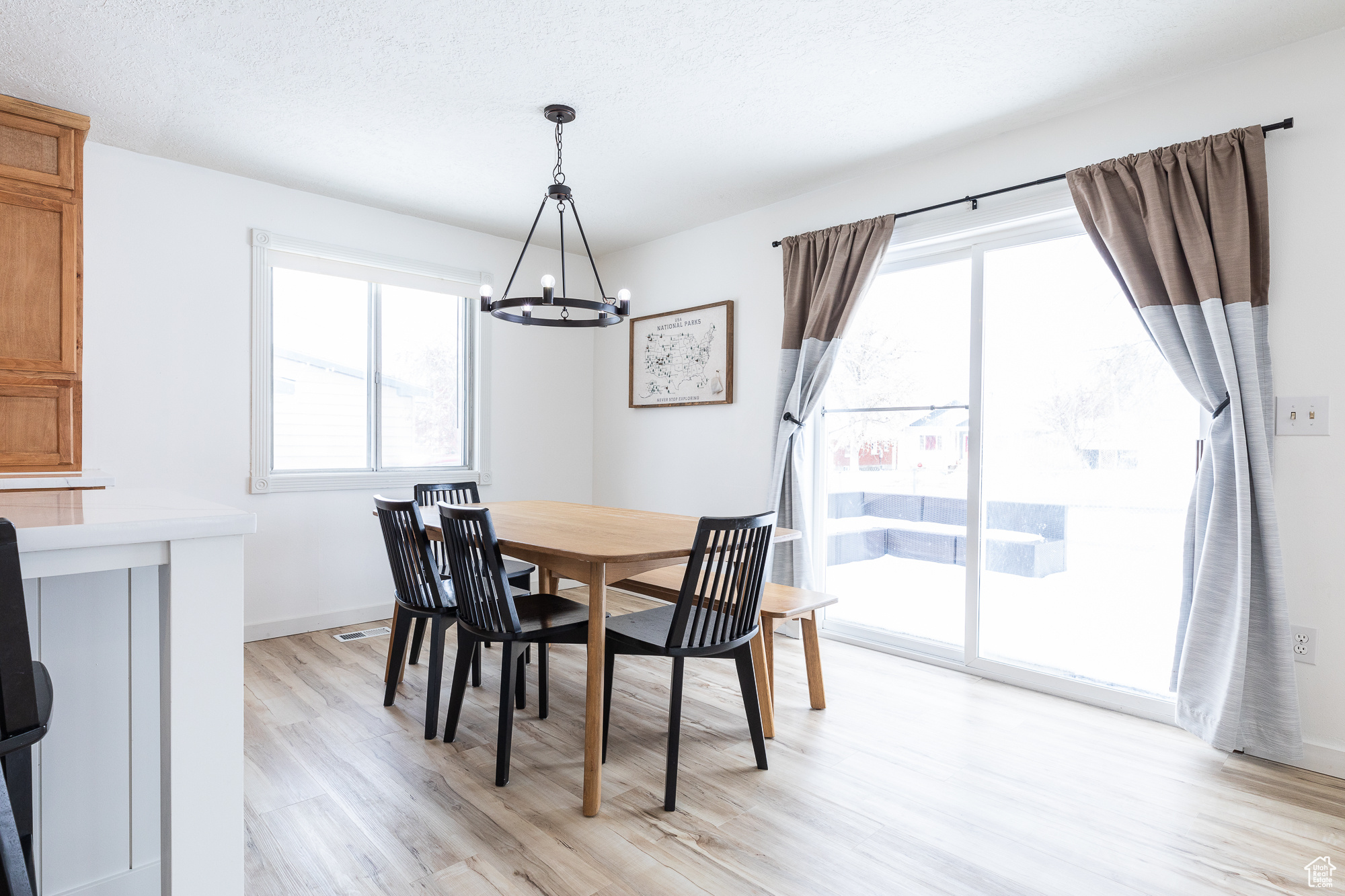 Dining space featuring baseboards, light wood finished floors, a textured ceiling, and an inviting chandelier