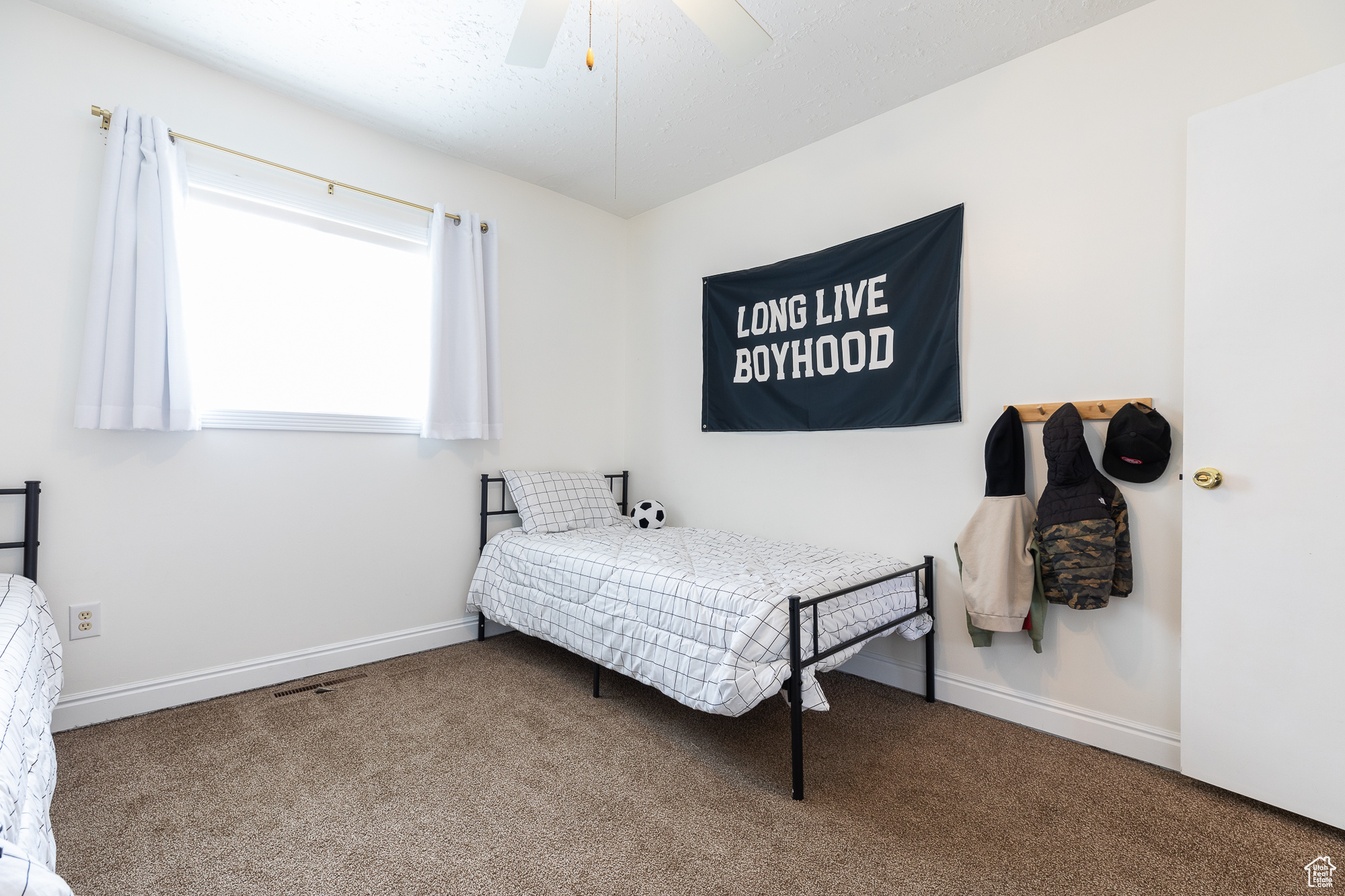 Carpeted bedroom featuring ceiling fan, a textured ceiling, and baseboards