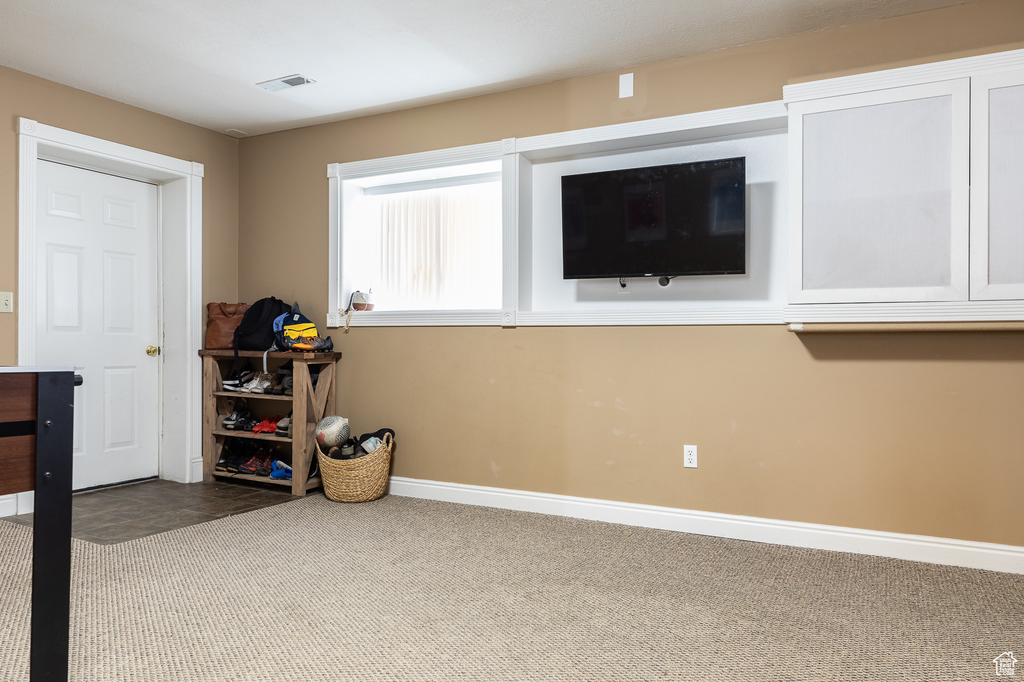 Interior space with baseboards, visible vents, and light colored carpet