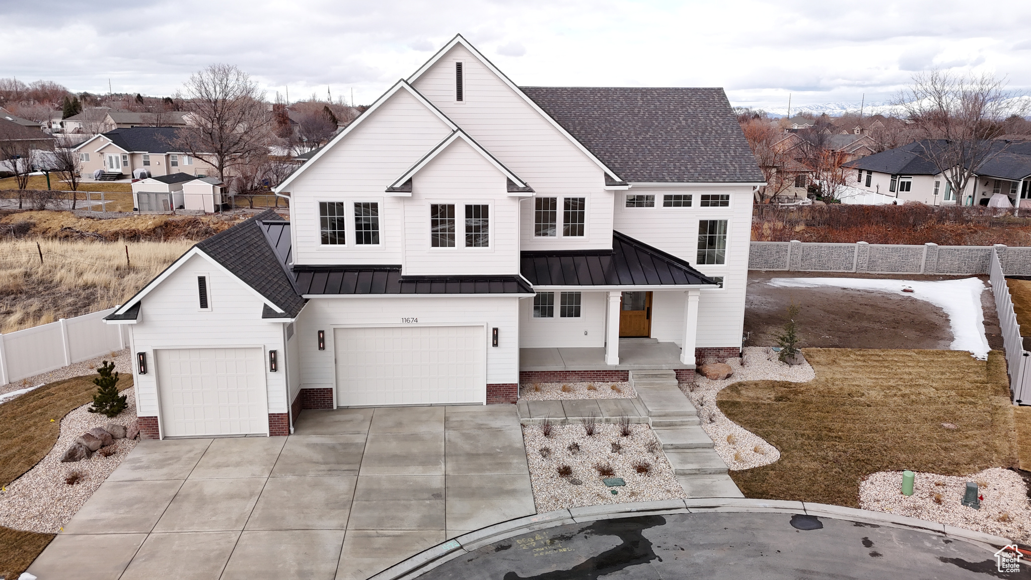 Modern farmhouse featuring a residential view, a standing seam roof, driveway, and fence