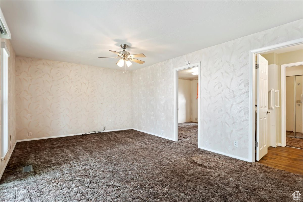 Carpeted spare room featuring visible vents, ceiling fan, and baseboards
