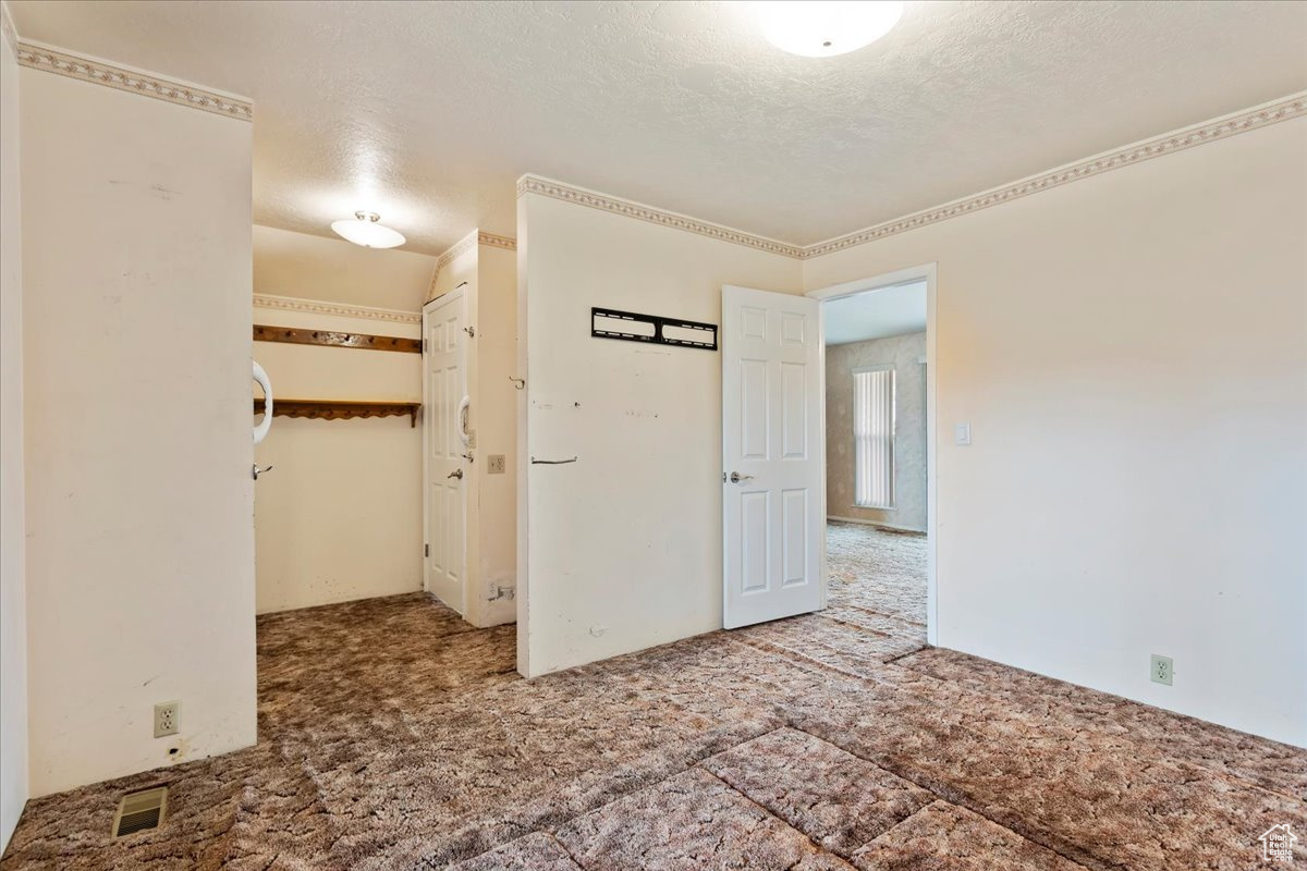 Unfurnished room featuring a textured ceiling, carpet, and visible vents