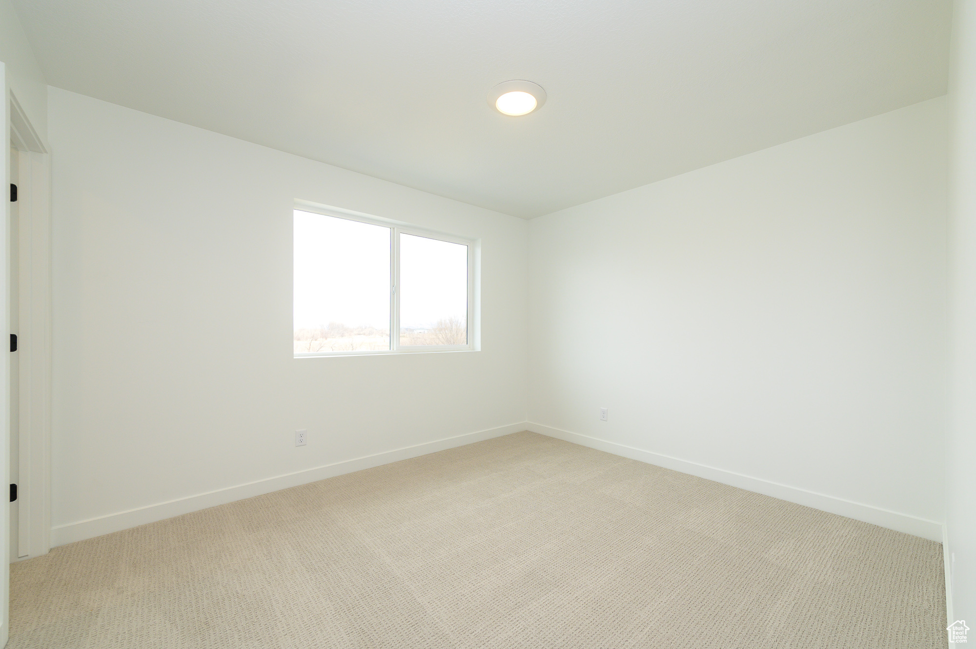 Spare room featuring light carpet and baseboards