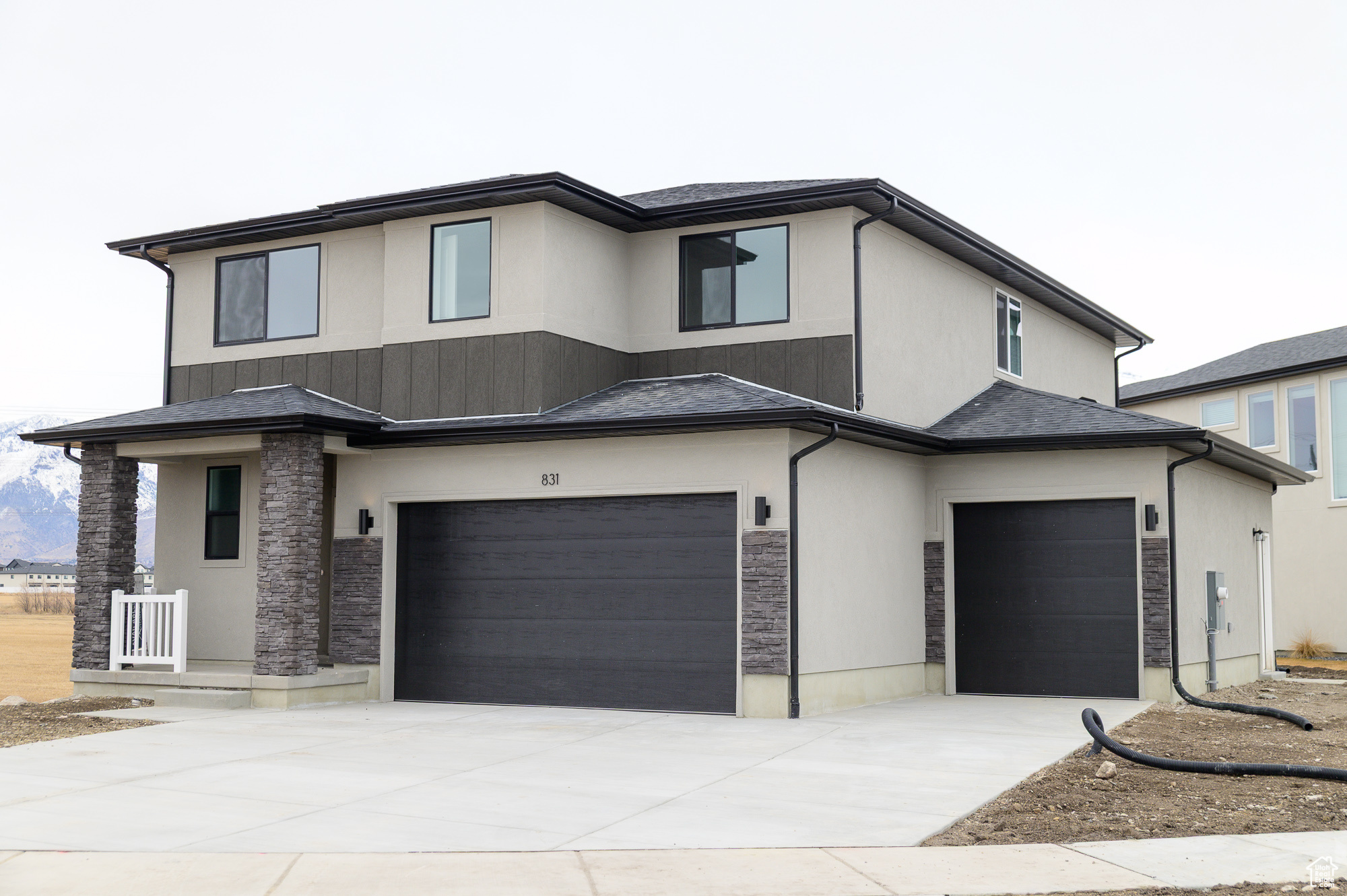 View of front of property featuring stone siding, stucco siding, concrete driveway, and a garage