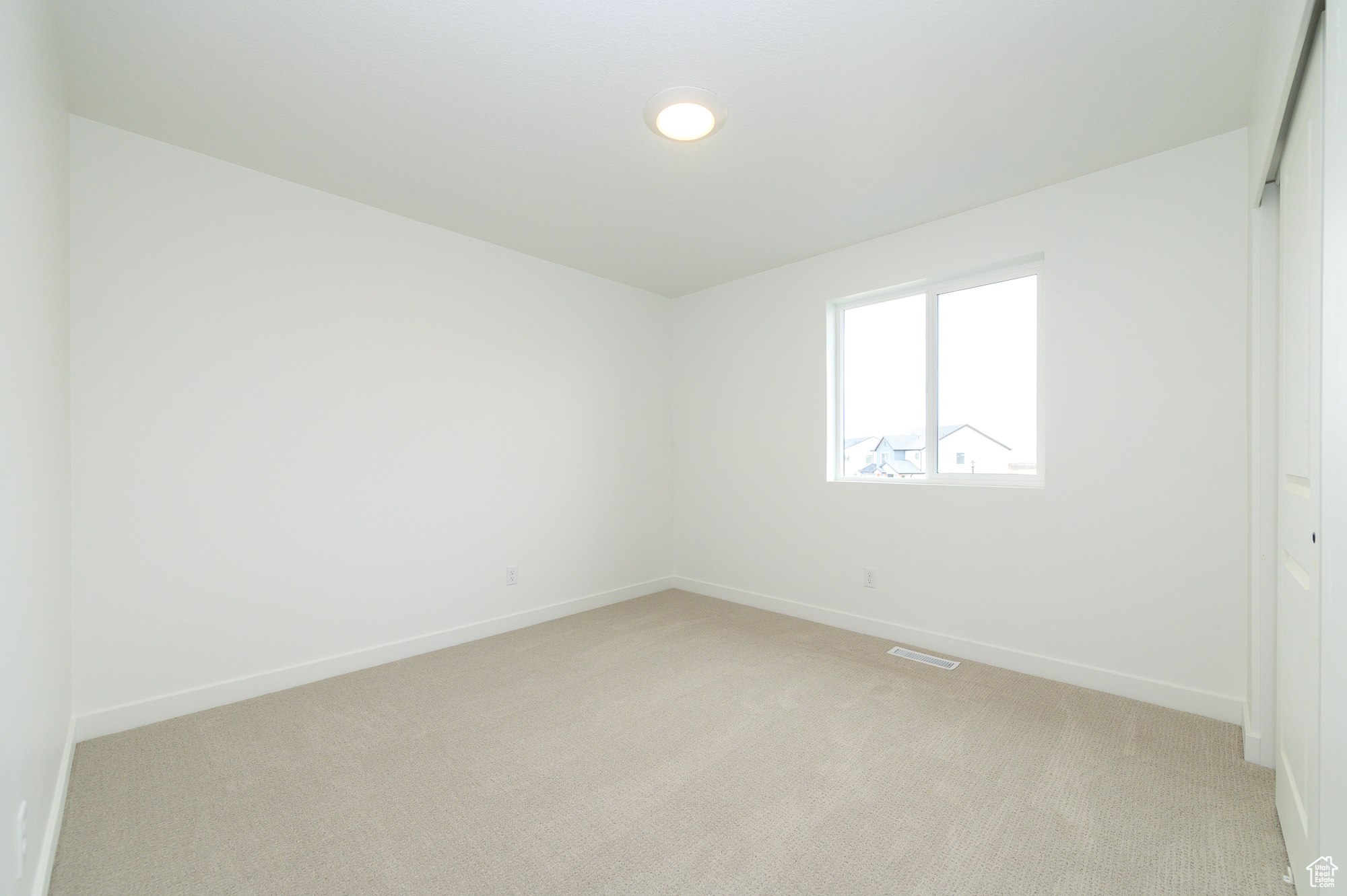 Empty room with visible vents, baseboards, and light colored carpet
