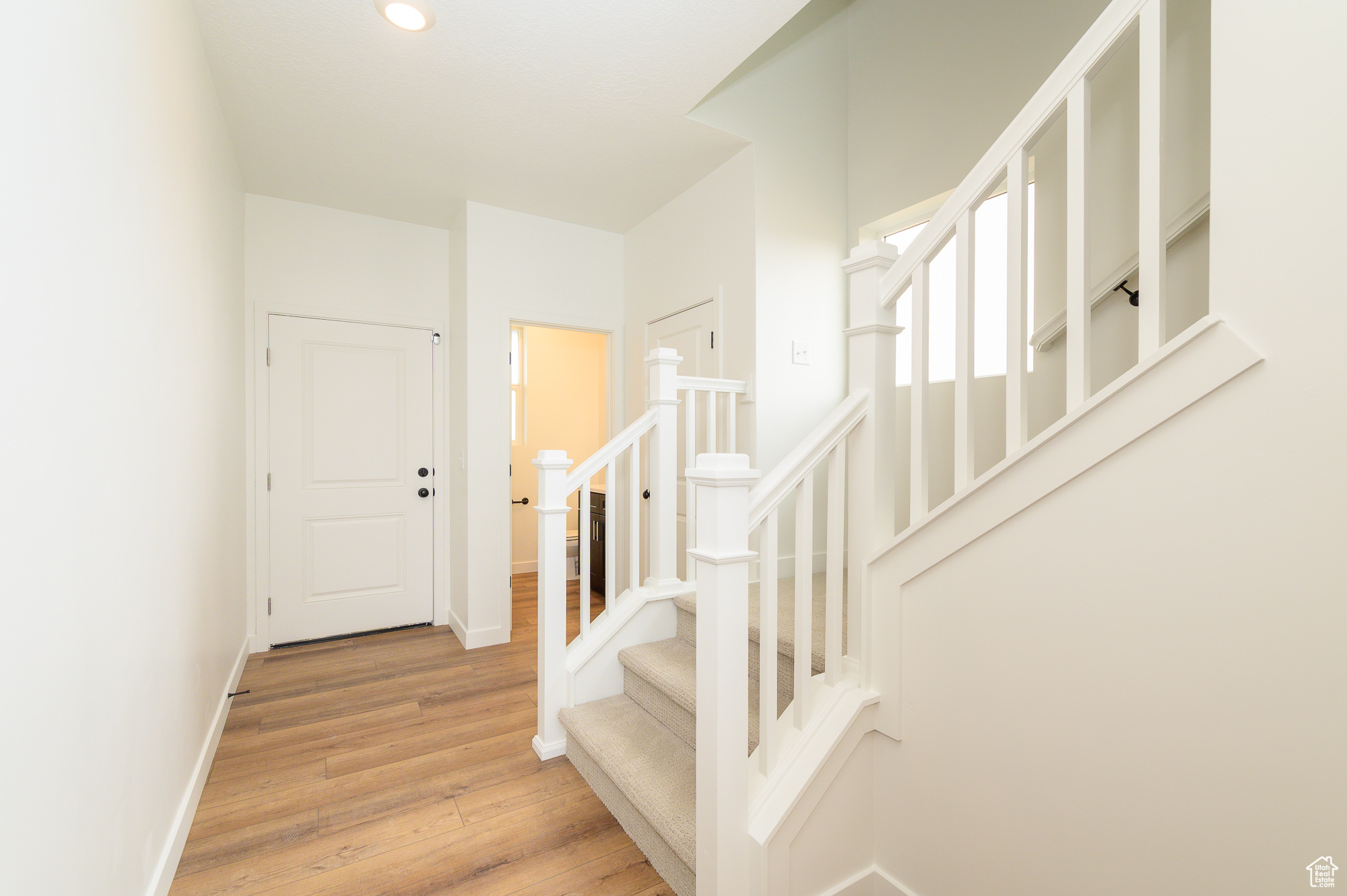Stairs with recessed lighting, wood finished floors, and baseboards