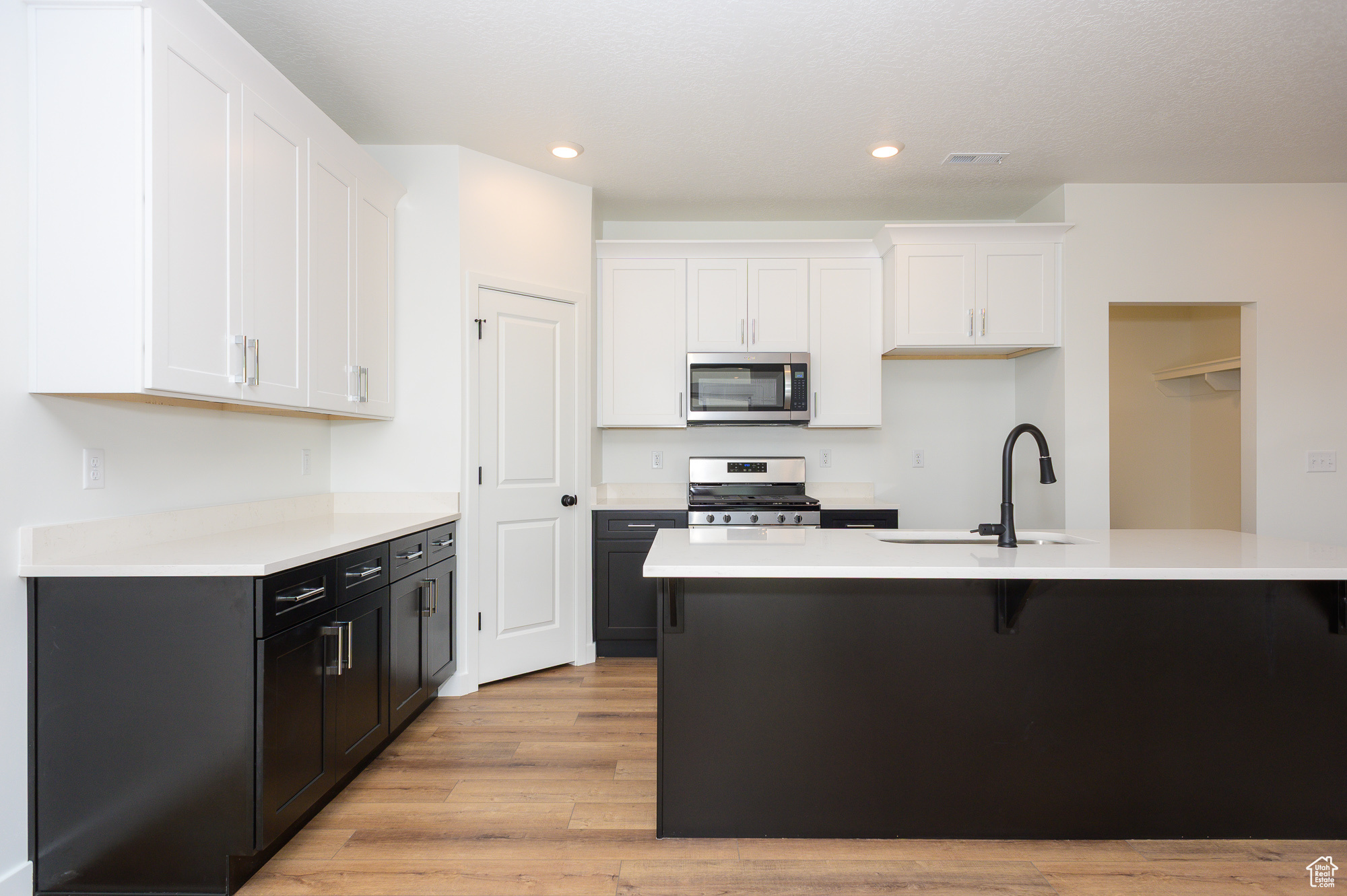 Kitchen with a center island with sink, appliances with stainless steel finishes, light countertops, and a sink