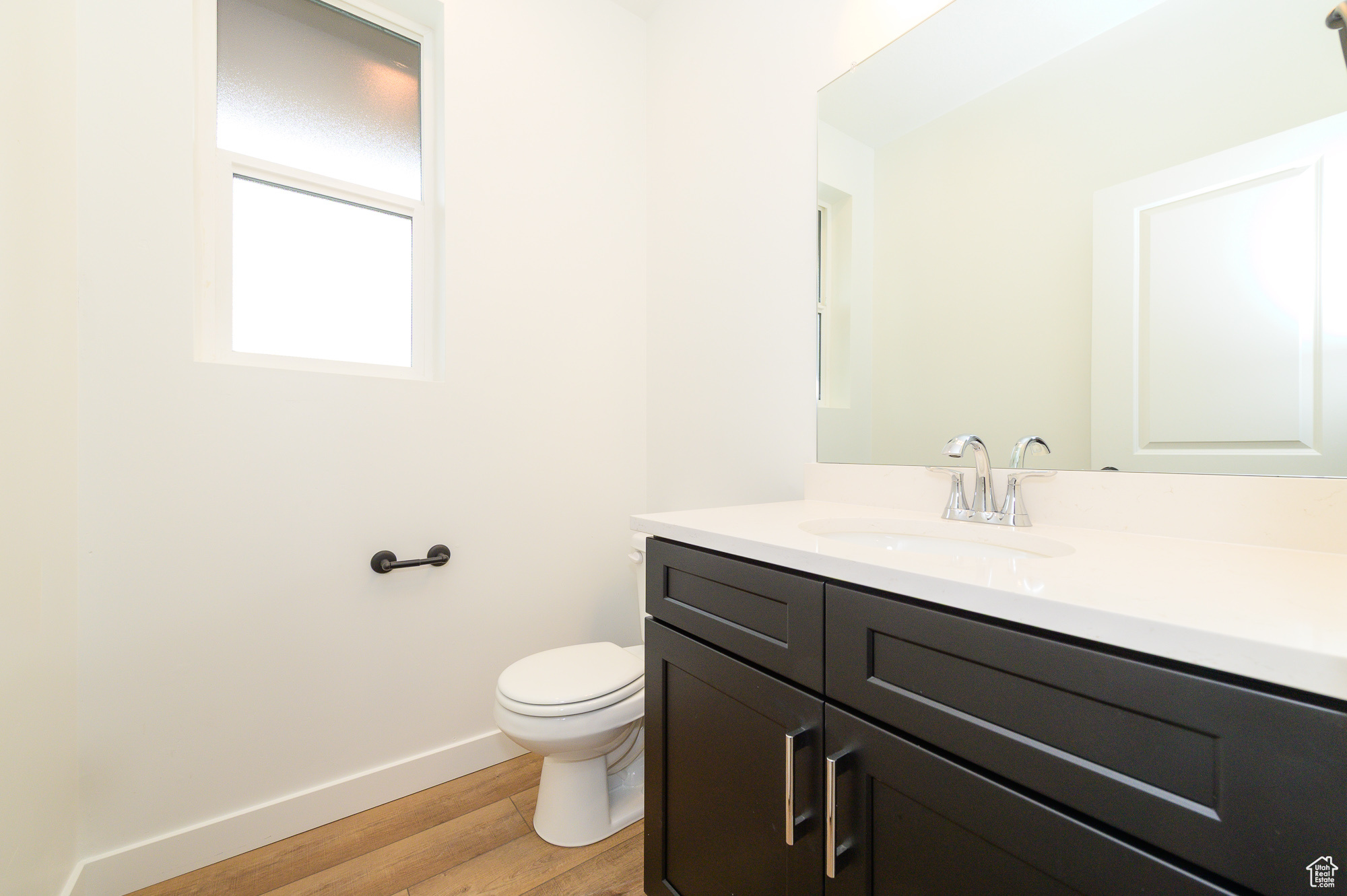 Half bath featuring vanity, wood finished floors, toilet, and baseboards