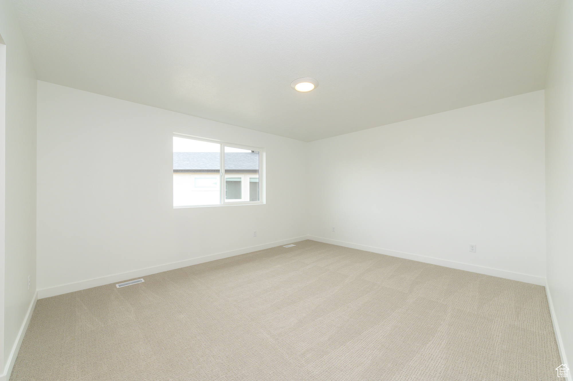 Spare room with baseboards, visible vents, and light colored carpet