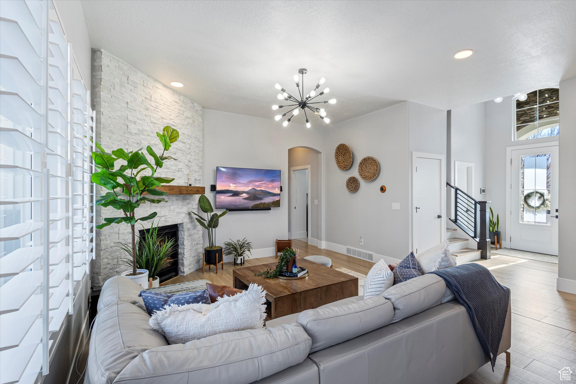 Living room with light wood-type flooring, a fireplace, and a chandelier