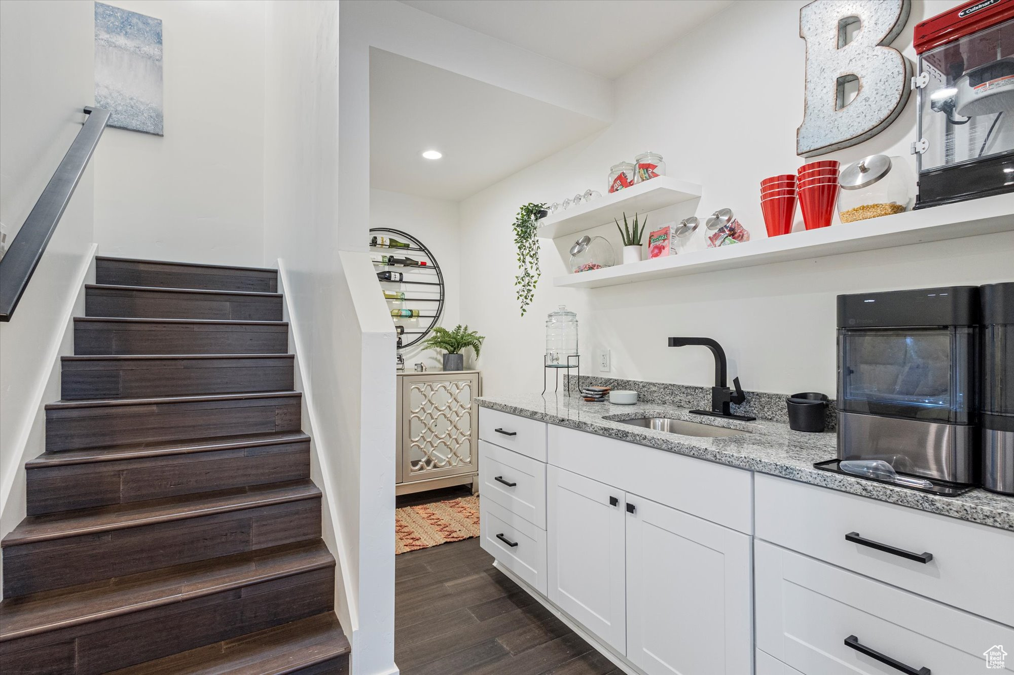 Kitchen featuring sink, dark wood-type flooring, white cabinets, and light stone counters