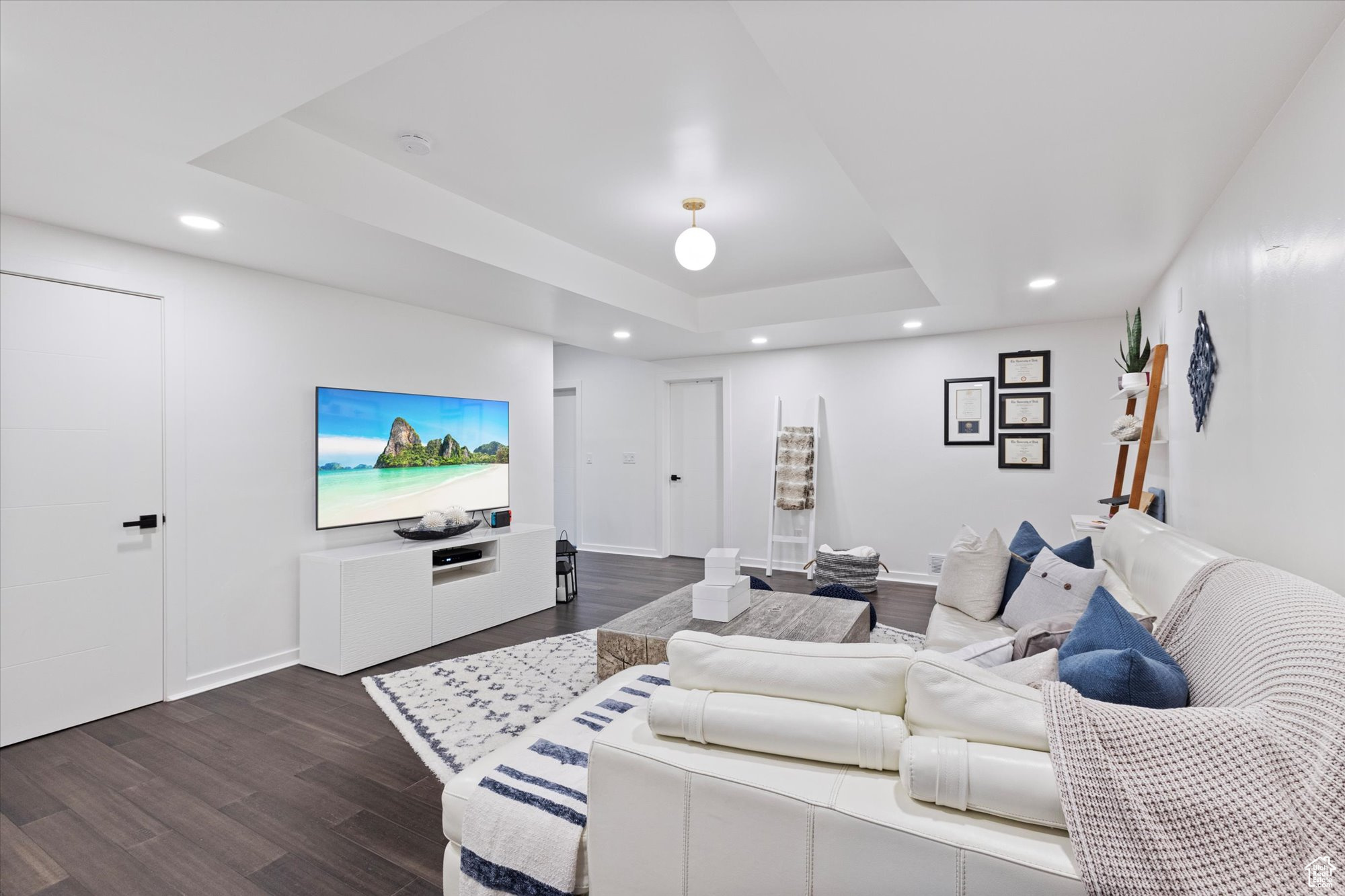 Living room with dark hardwood / wood-style floors and a tray ceiling