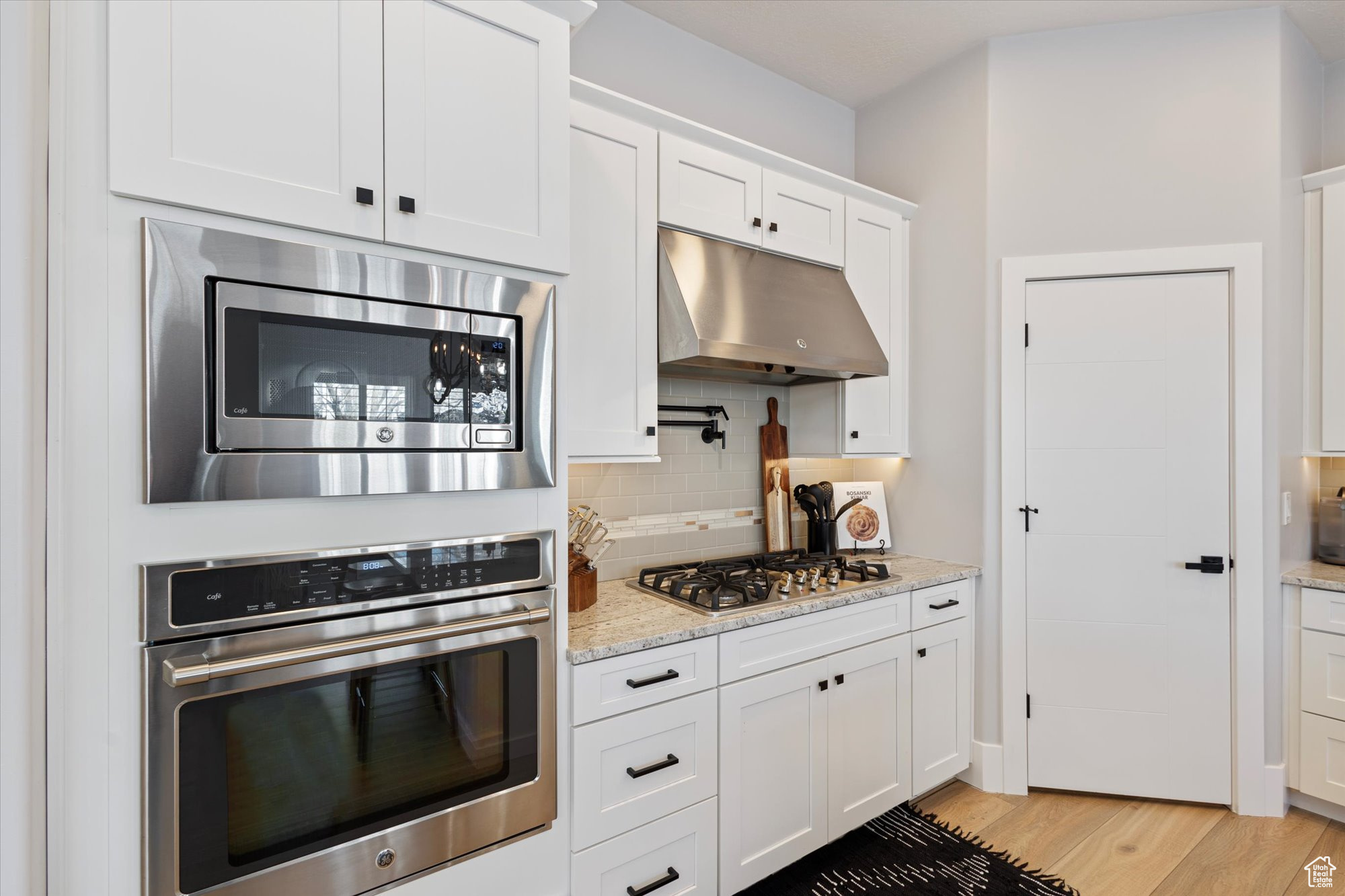 Kitchen with white cabinetry, stainless steel appliances, and light stone countertops