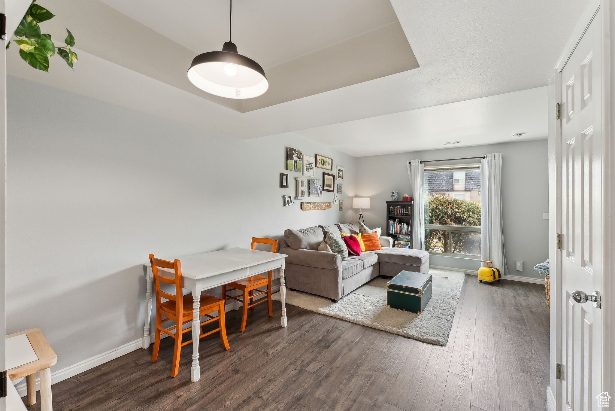 Living room featuring dark wood-style floors, baseboards, and a raised ceiling