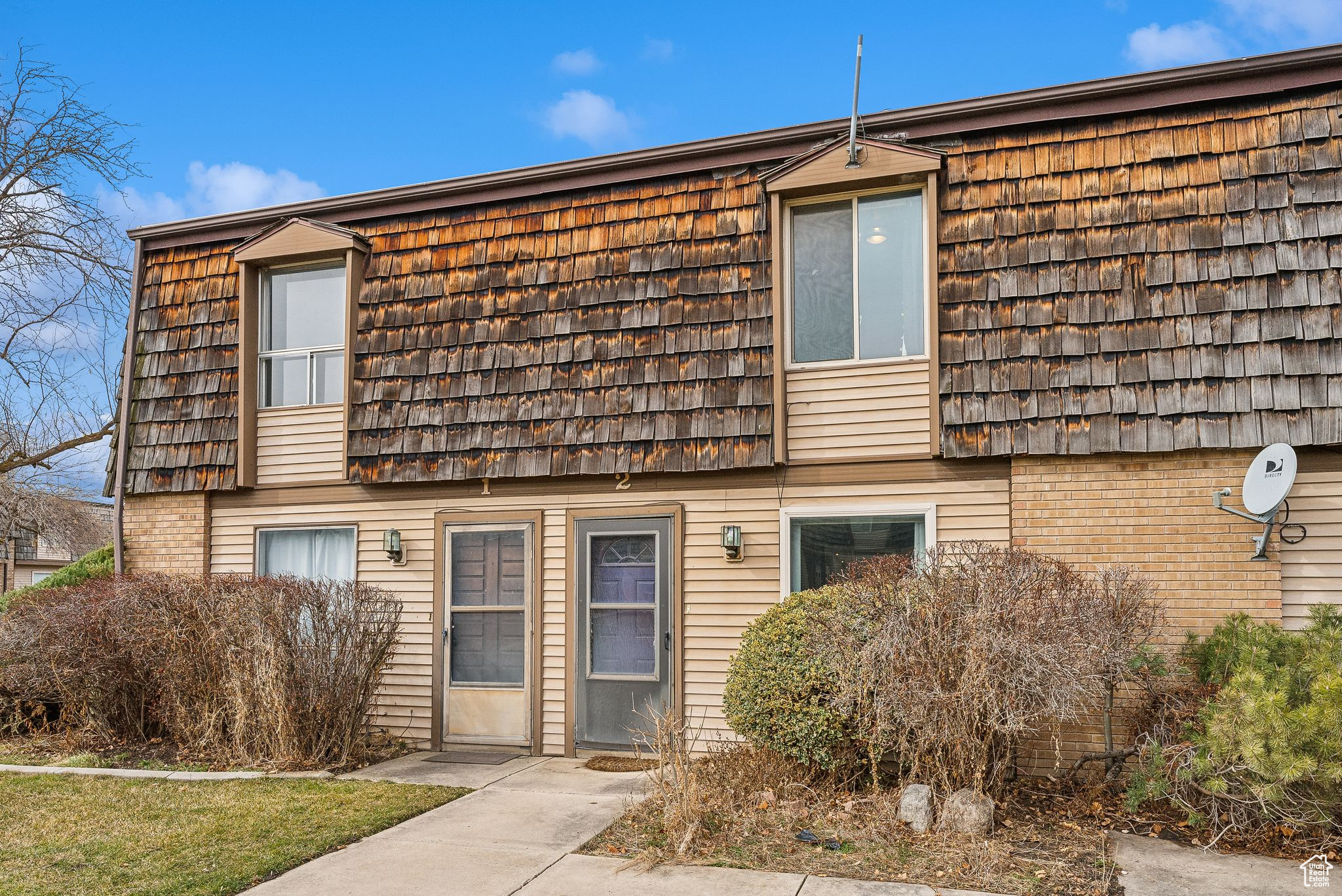 Townhome / multi-family property with mansard roof and brick siding