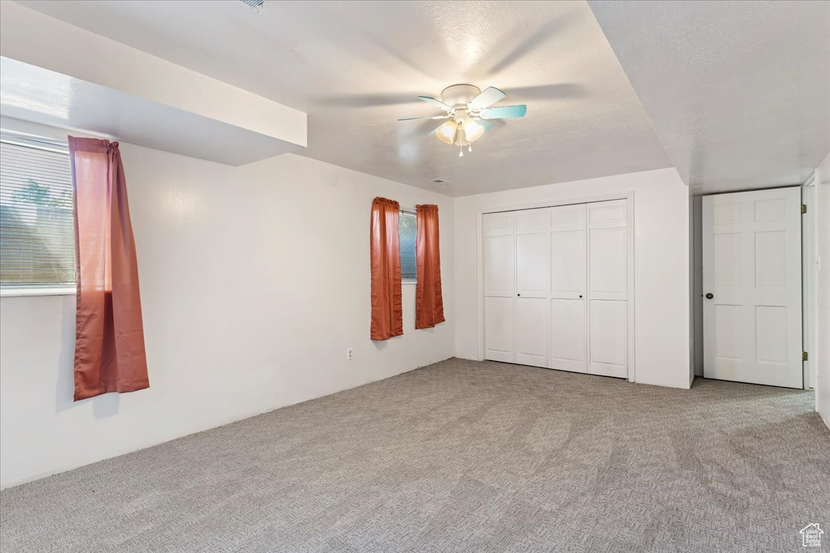 Unfurnished bedroom featuring carpet, ceiling fan, and a closet