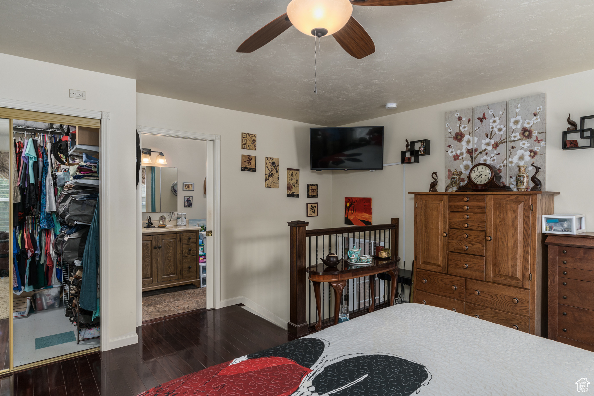 Bedroom featuring dark wood-style floors, a closet, ceiling fan, ensuite bath, and baseboards