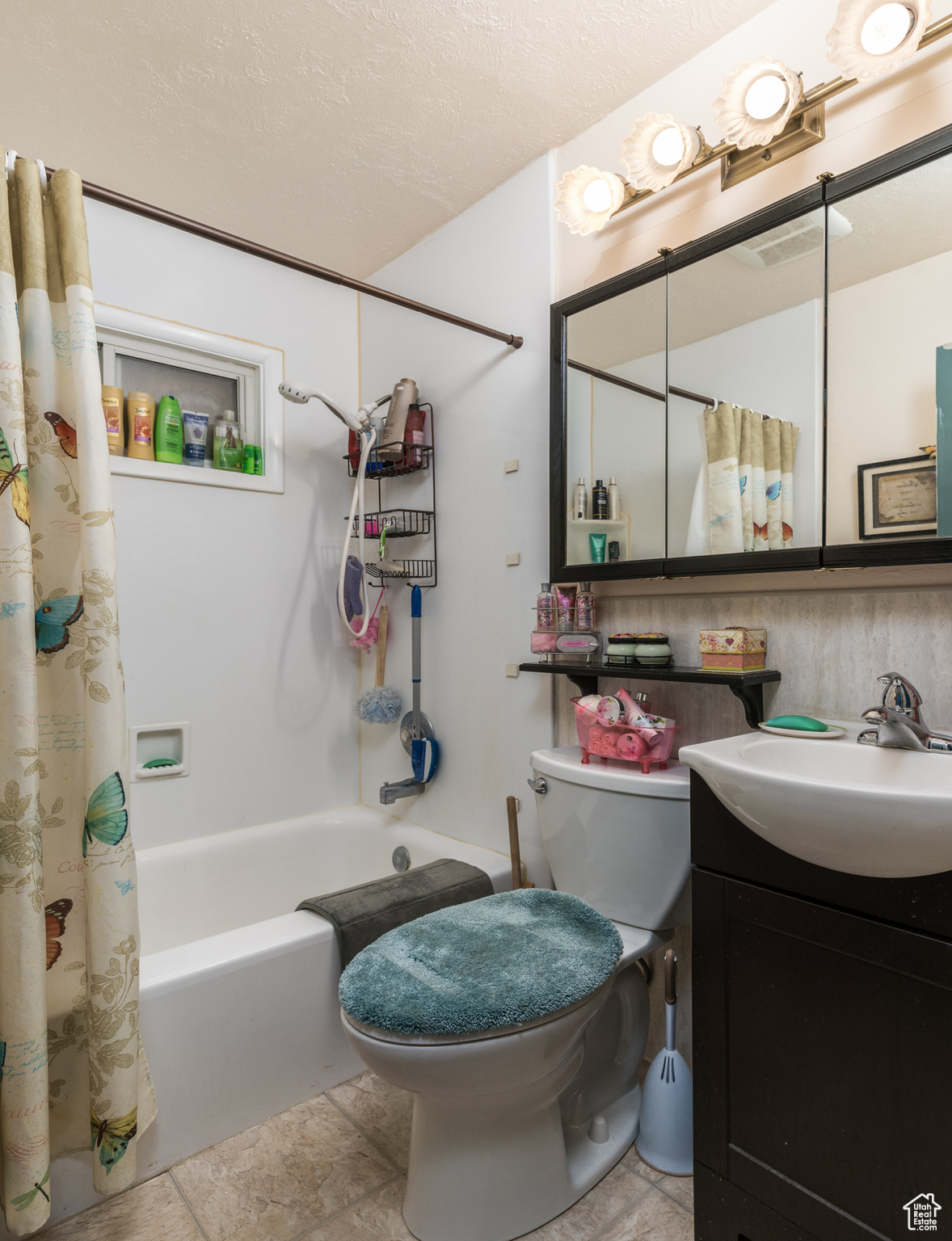 Bathroom featuring shower / bath combo, vanity, toilet, and a textured ceiling