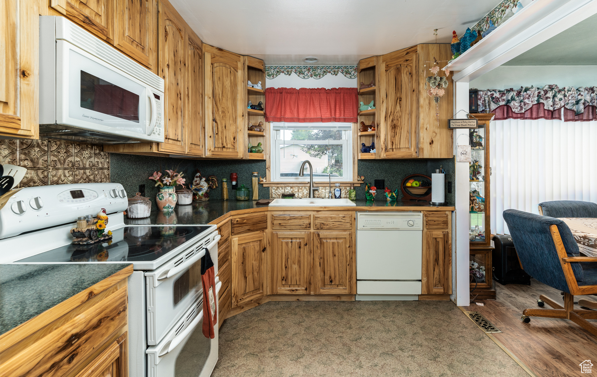 Kitchen with white appliances, a sink, open shelves, tasteful backsplash, and dark countertops