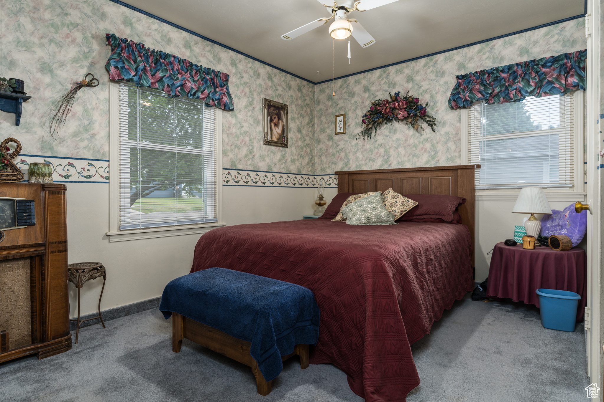 Bedroom with light carpet, wallpapered walls, ceiling fan, and baseboards