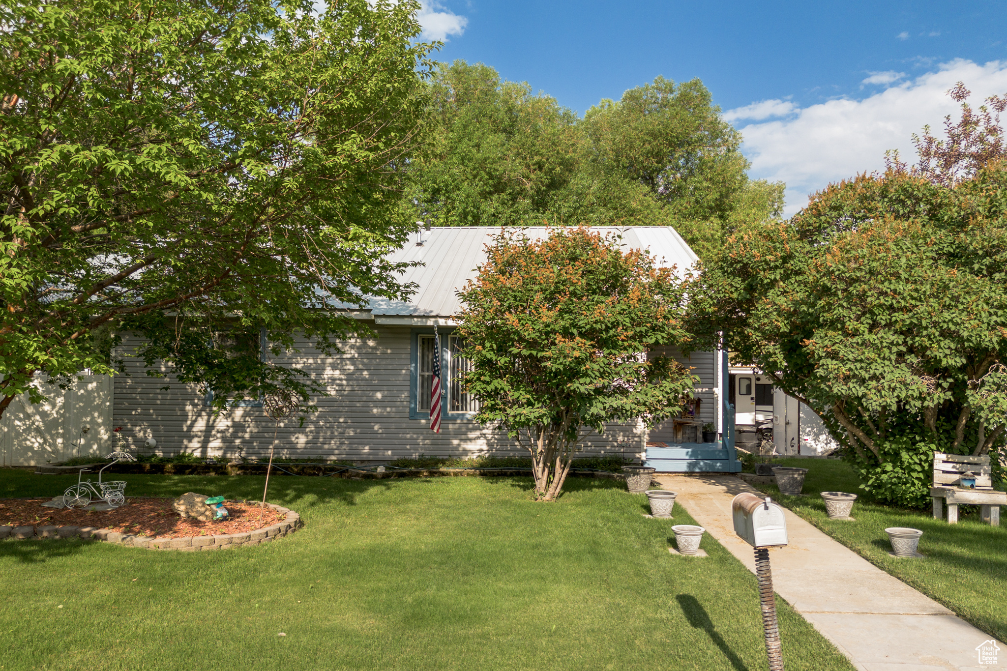 Obstructed view of property featuring a front yard and metal roof
