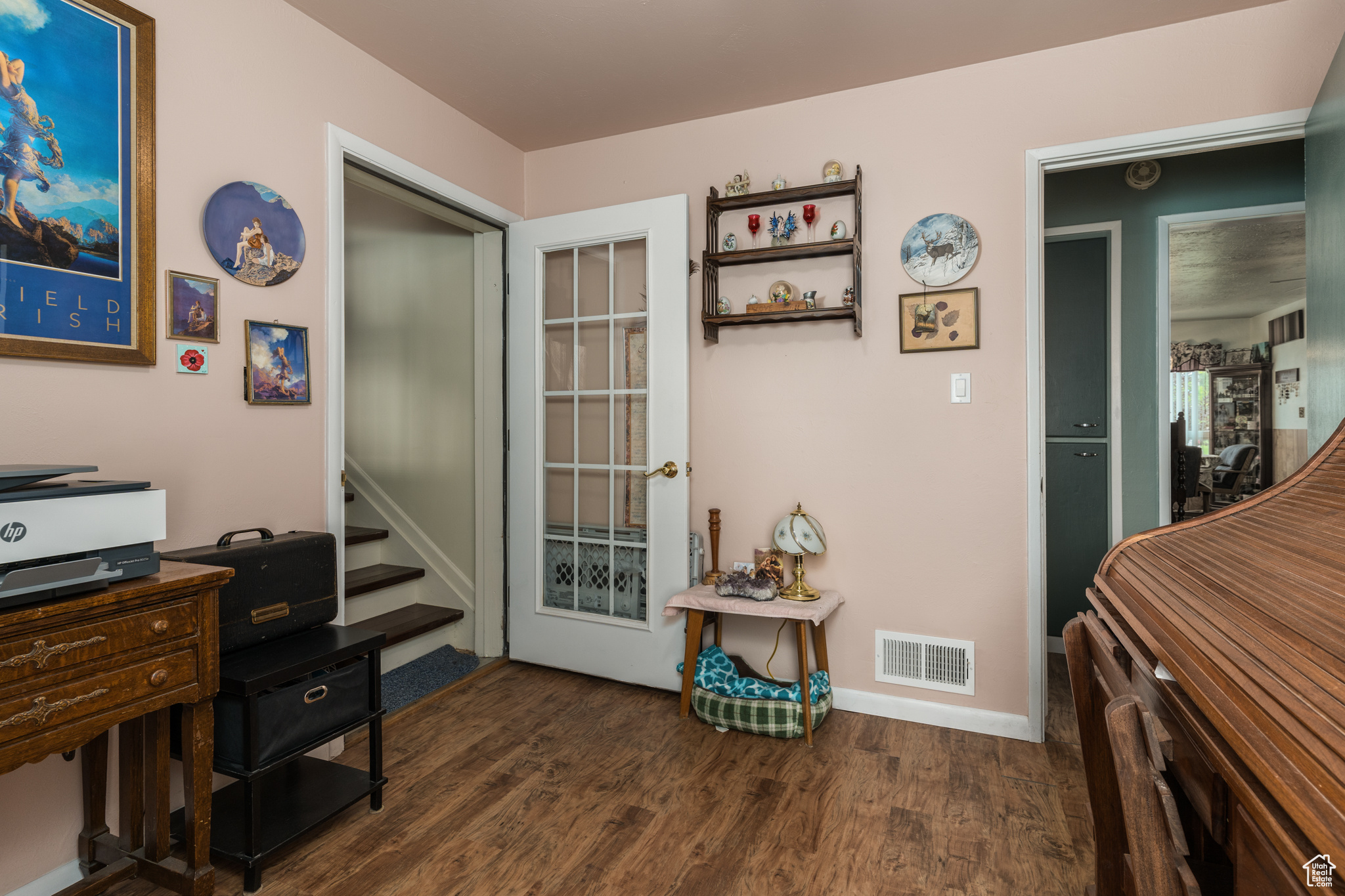 Office with dark wood-style floors, visible vents, and baseboards