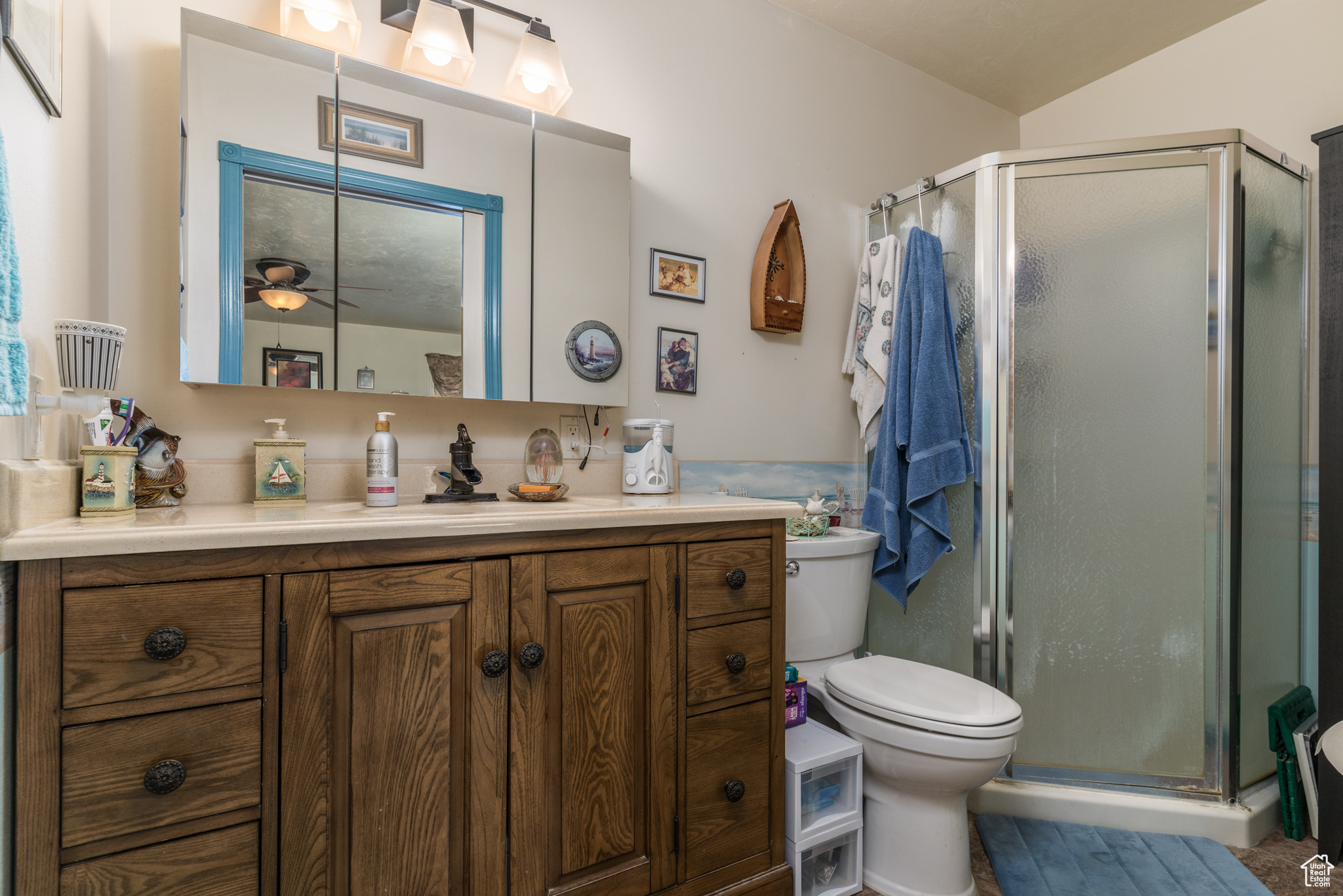 Full bathroom featuring a ceiling fan, a stall shower, vanity, and toilet