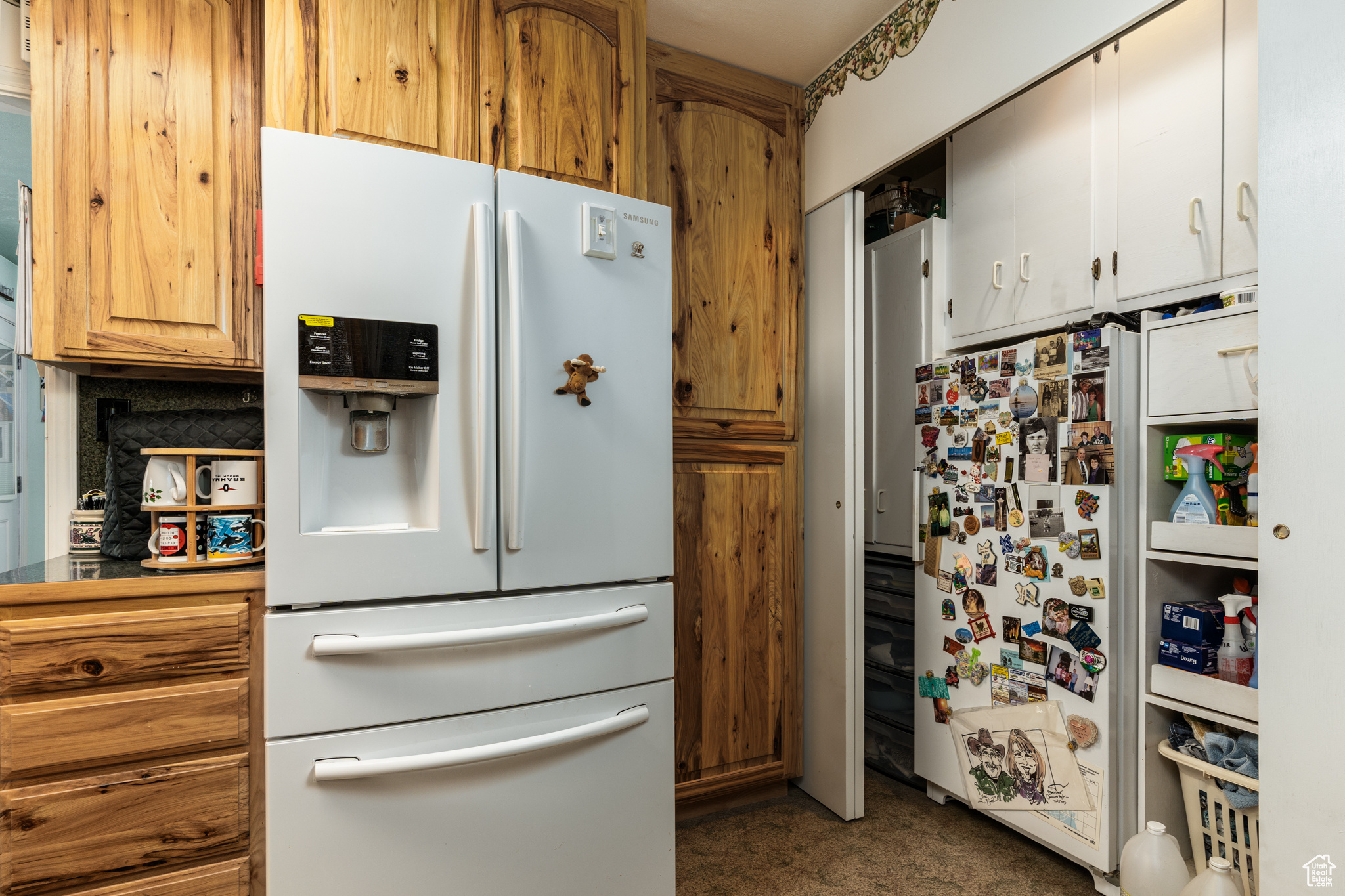 Kitchen with brown cabinetry, freestanding refrigerator, and white refrigerator with ice dispenser